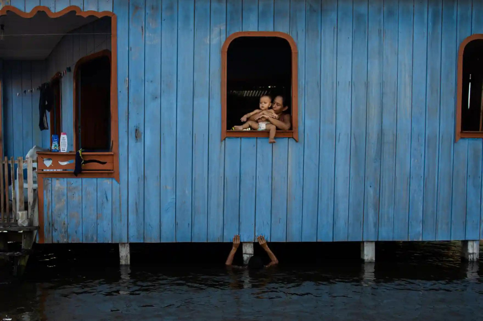 Categoría clima: 
Raphael Alves capturó el momento en que una mujer observa, desde la ventana de su casa, a su hijo jugar en la crecida de los ríos, en Anama, Brasil.