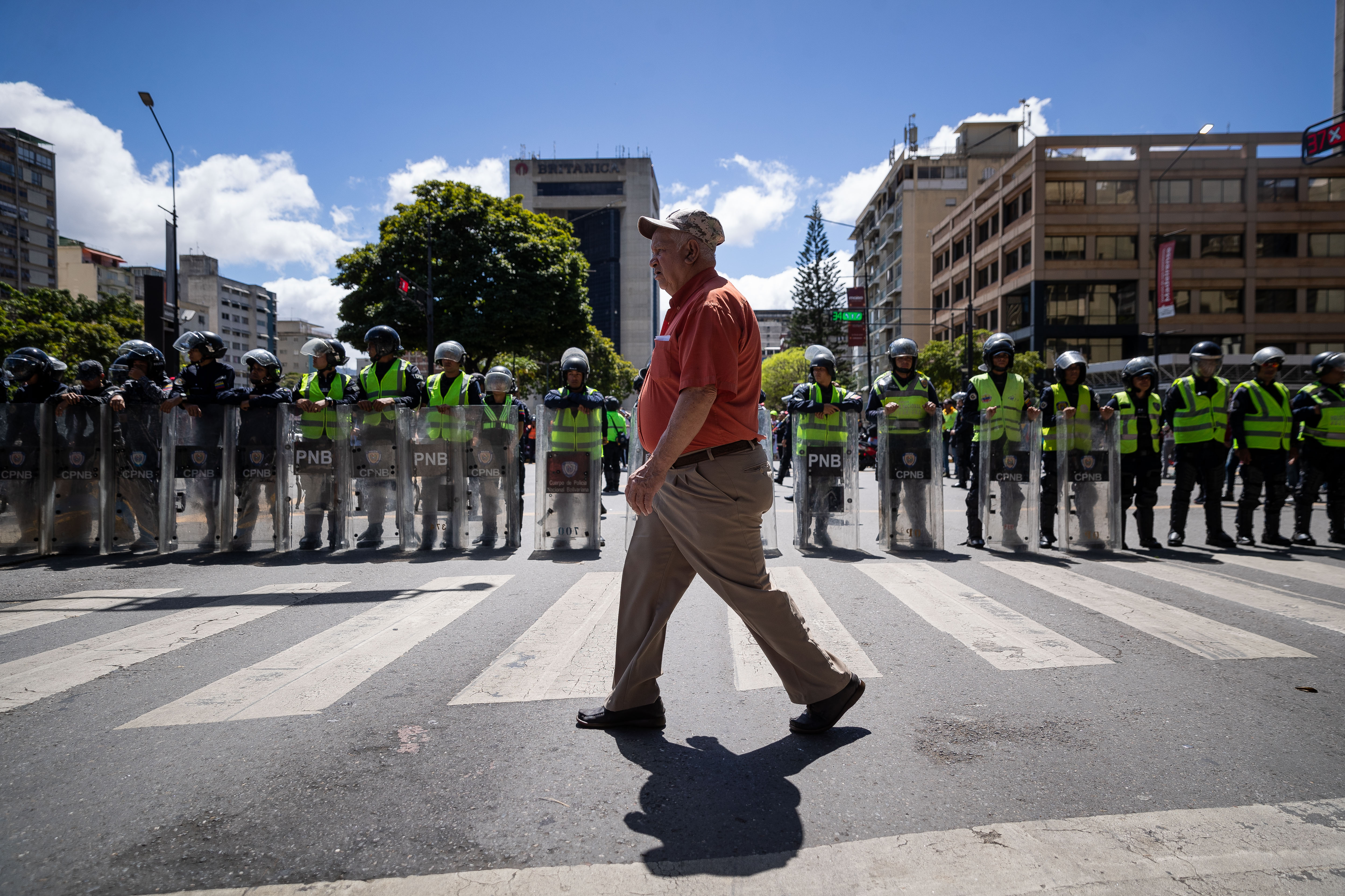 -FOTODELDÍA- AME1640. CARACAS (VENEZUELA), 23/01/2024.- Un hombre camina frente a un cordón policial que separa una marcha oficialista de una concetración opositora, hoy, en Caracas (Venezuela). El chavismo y la oposición calentaron motores y mostraron sus fuerzas este martes con sendas movilizaciones en Caracas y varias regiones de Venezuela, de cara a unas elecciones presidenciales previstas para el segundo semestre del año, aún sin una fecha definida. EFE/ Rayner Peña R.
