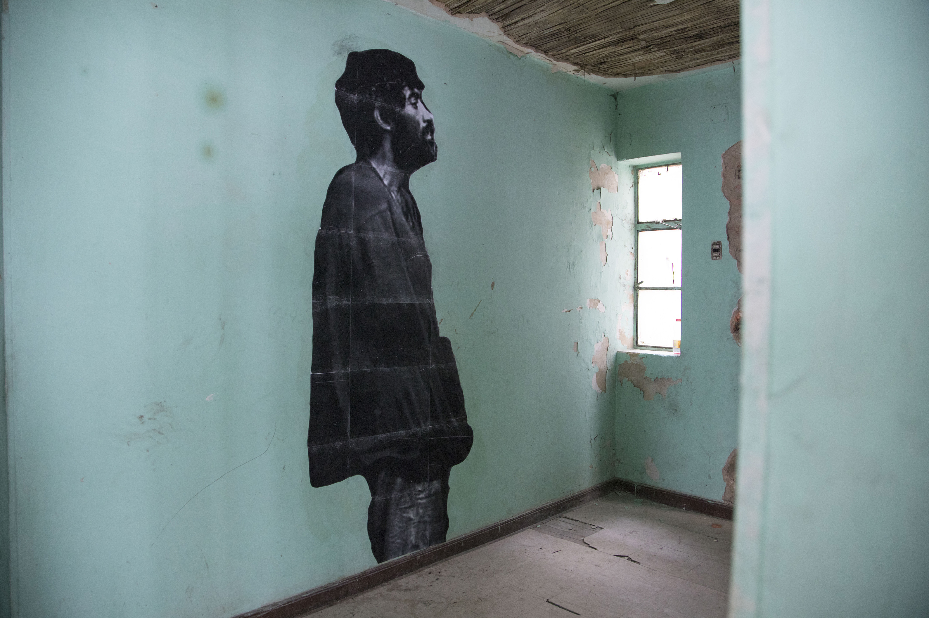 Una foto en blanco y negro de un hombre pegada en una pared verde.