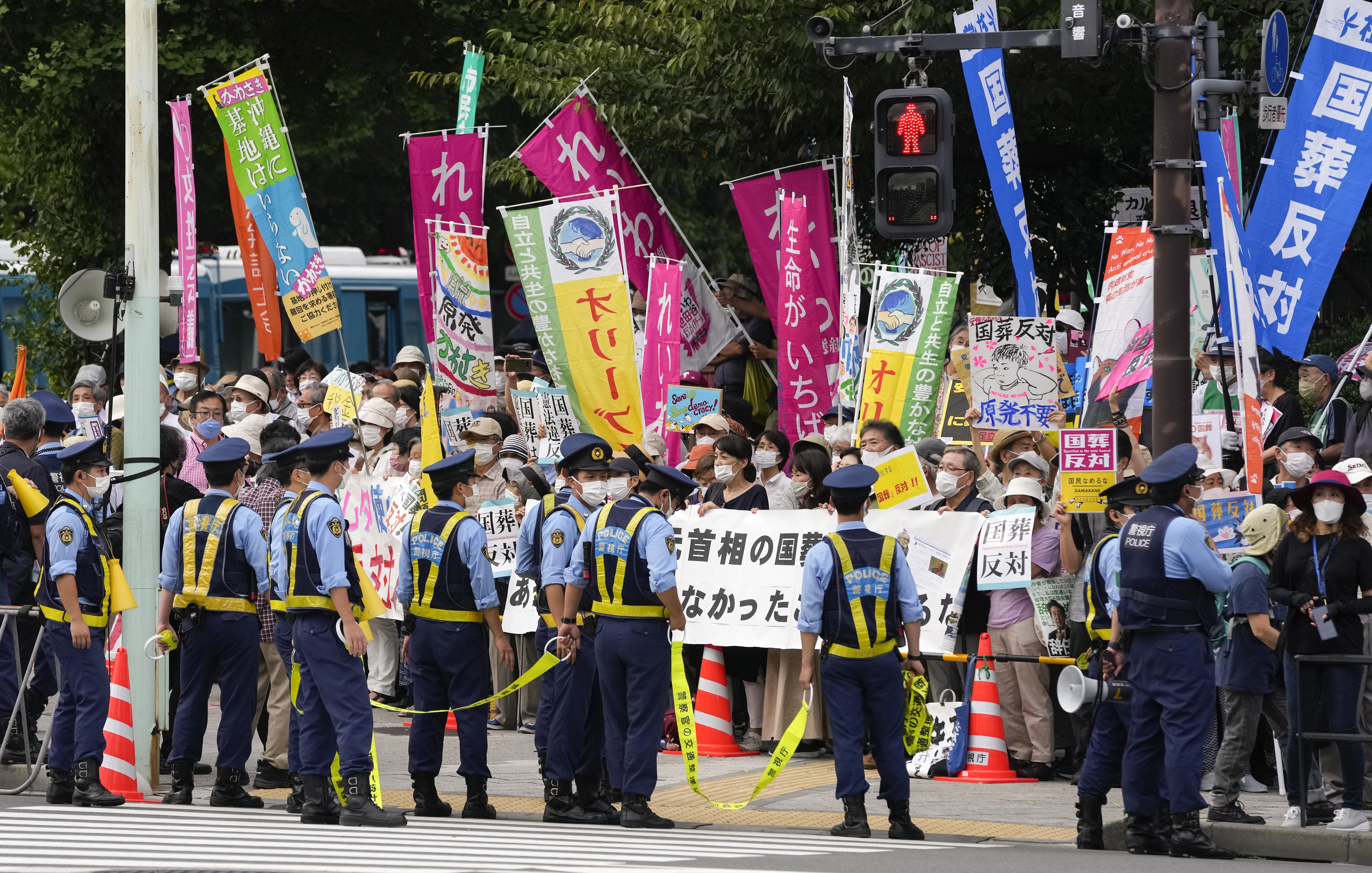 Tokyo (Japan), 27/09/2022.- Police officers stand guard in front of protesters holding placards reading 'No!! State funeral' during a rally against the state funeral of former Prime Minister Shinzo Abe in Tokyo, Japan, 27 September 2022. Thousands of people gathered to attend the state funeral of former prime minister Shinzo Abe, including foreign dignitaries and representatives from more than 200 countries and international organizations, despite protests across the country against the highly controversial event. (Protestas, Japón, Estados Unidos, Tokio) EFE/EPA/KIMIMASA MAYAMA