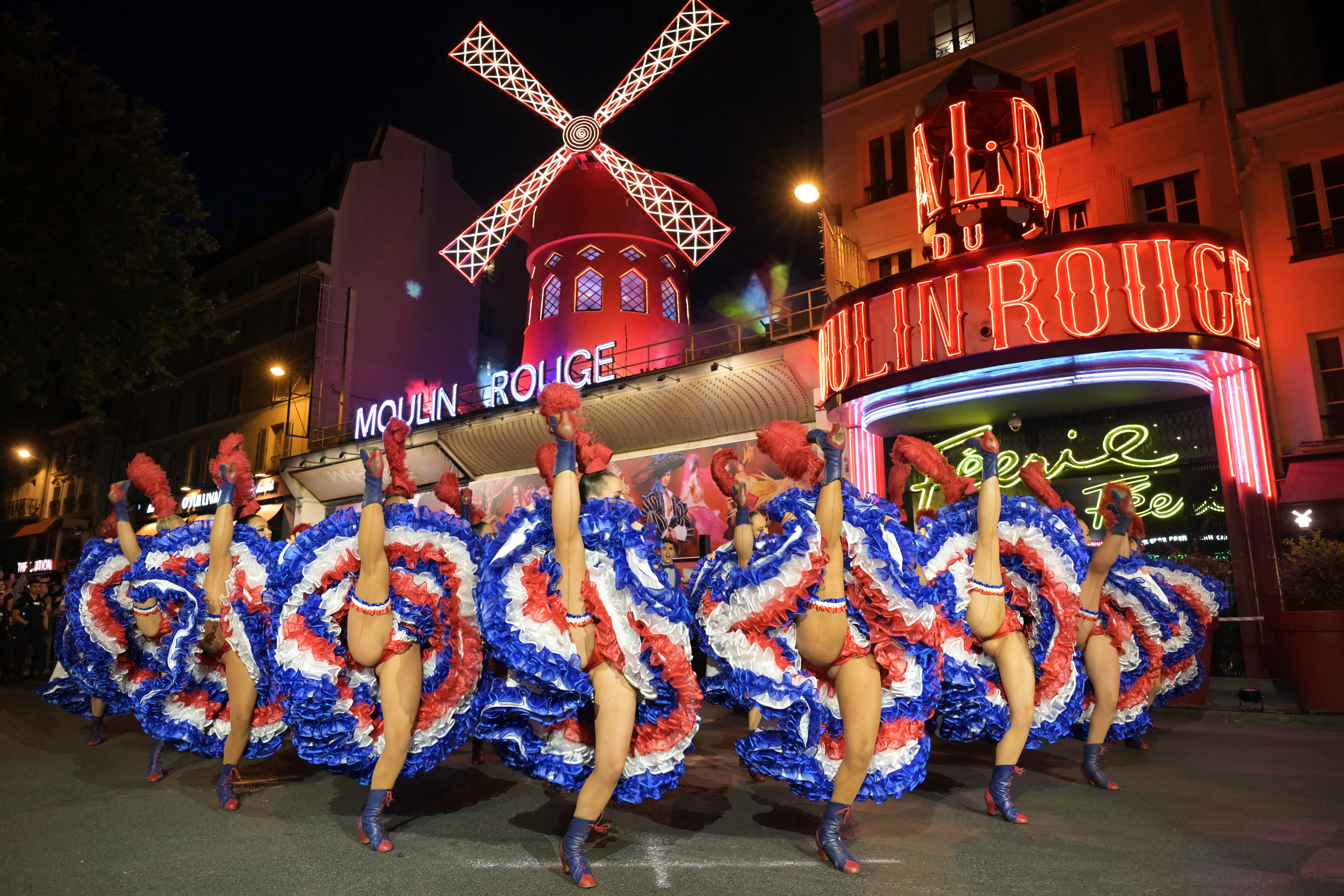 TOPSHOT - Dancers perform in front of the Moulin Rouge cabaret during the inauguration of the theatre's windmill sails in Paris on July 5, 2024, an event that marks the return of the cabaret lights ahead of the Paris 2024 Olympic Games after the collapse of the former windmill sails last April.