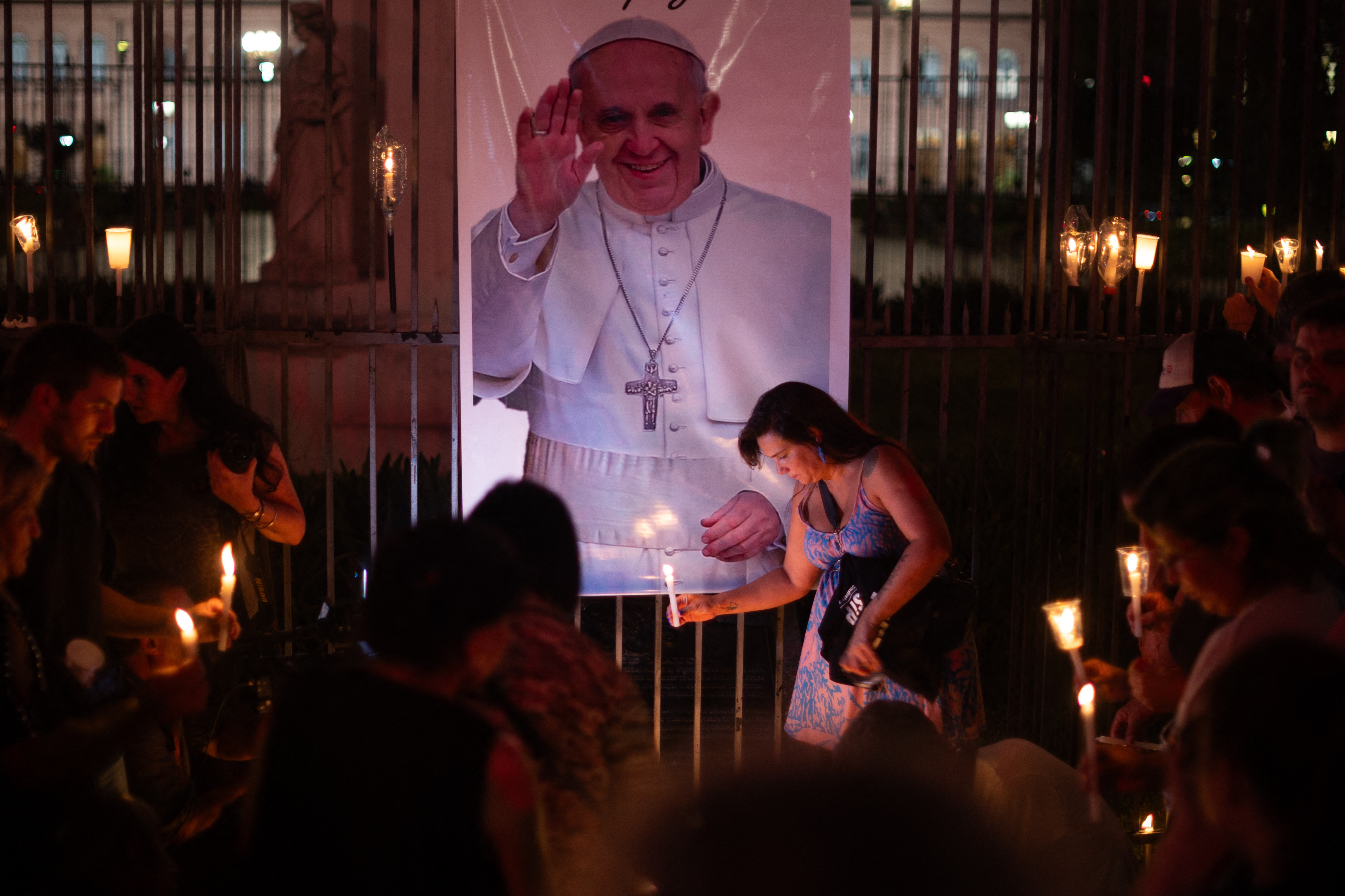 People place lit candles close to a picture of Pope Francis during a vigil to pray for his health in Buenos Aires on March 7, 2025.