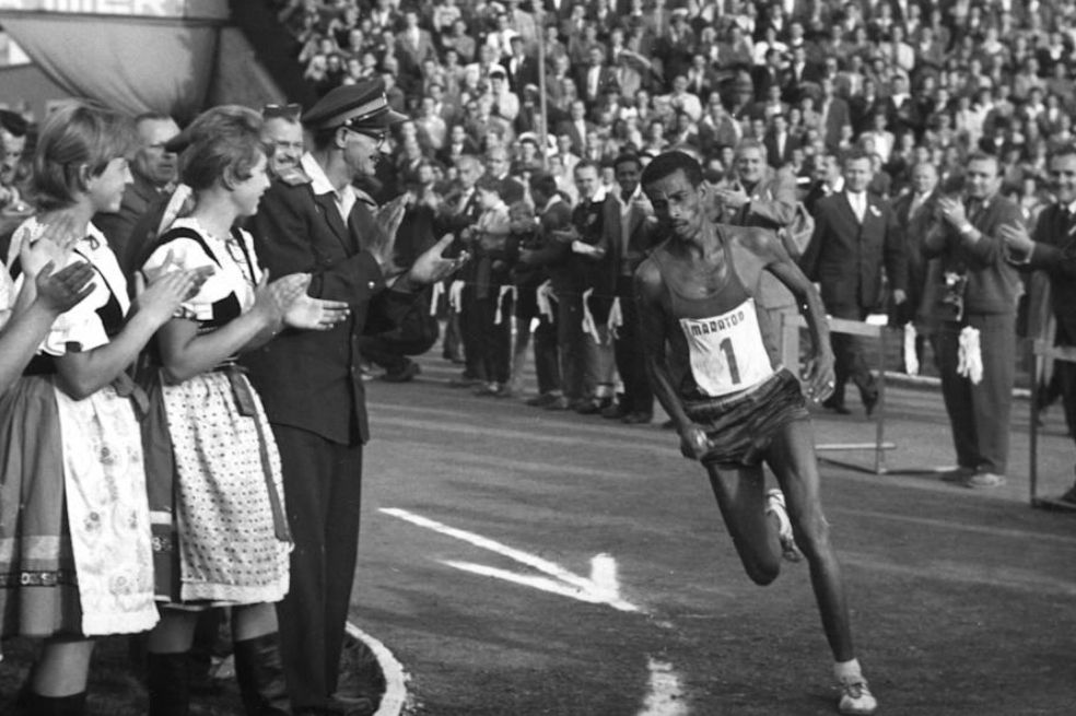 Primer atleta africano en ganar una medalla de oro, el etíope Abebe Bikila fue campeón en dos oportunidades del maratón en los Juegos Olímpicos de Roma en 1960 y en Tokio 1964. Icónica fue la imagen que dejó en Italia cuando en plena prueba pasó por el frente del obelisco de Axum, que fue ​robado a su país natal en 1937 por el ejército italiano durante la Segunda Guerra Ítalo Abisinia.