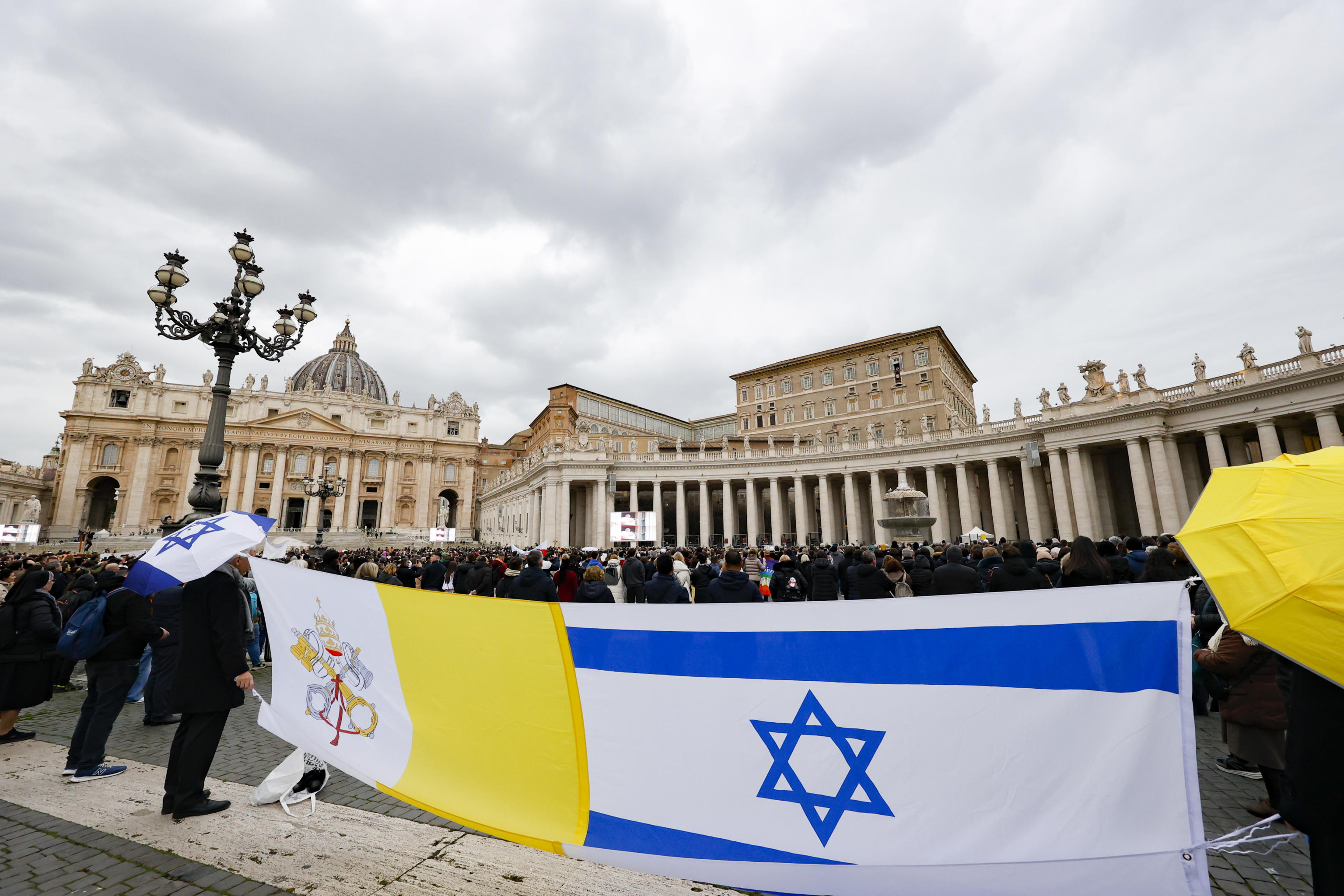 Vatican City (Italy), 19/01/2025.- People hold flags of Vatican City and Israel as Pope Francis leads the Angelus prayer, traditional Sunday's prayer, from the window of his office overlooking Saint Peter's Square, in Vatican City, 19 January 2025. (Papa) EFE/EPA/FABIO FRUSTACI