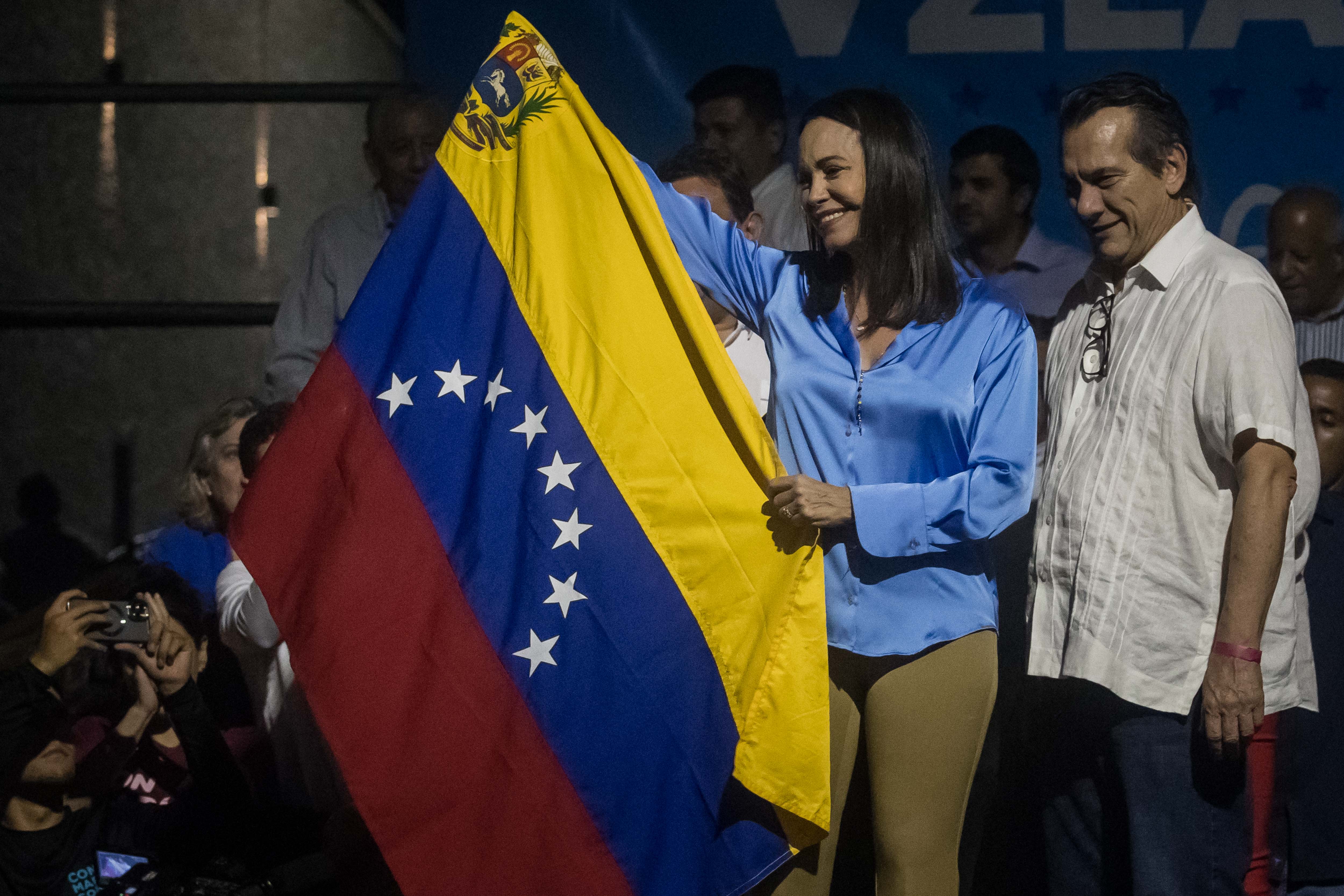 CARACAS (VENEZUELA) 23/10/2023 - La exdiputada Maria Corina Machado (c) sonríe mientras celebra junto a aliados y seguidores en las primeras horas de este lunes los resultados ofrecidos por la comisión de elecciones primarias, en Caracas (Venezuela). La exdiputada María Corina Machado es la gran triunfadora de las primarias opositoras de este domingo en Venezuela, con el 93,13 % de los votos, con un 26,06 % de las actas escrutadas, de unas votaciones en las que los venezolanos eligieron a quien debe enfrentarse al chavismo en las presidenciales de 2024. EFE/ Miguel Gutiérrez