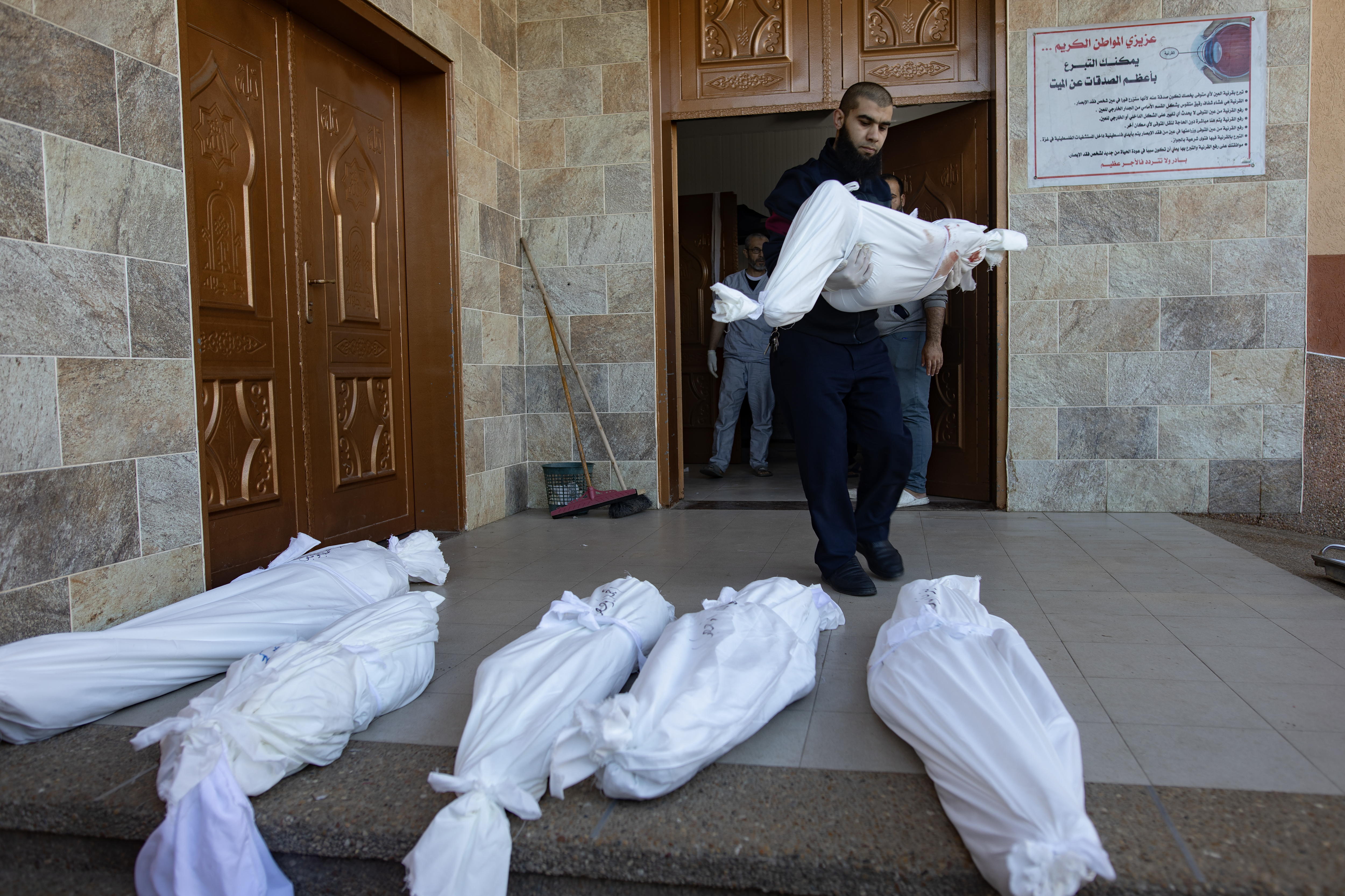 Khan Yunis (-), 04/01/2024.- Morgue staff at Nasser Hospital carry out of the morgue the wrapped bodies of Abu Hatab family members, who were killed during an Israeli air strike that targeted areas classified by the Israeli army as safe in the southern Gaza Strip, in Khan Younis, southern Gaza Strip, 04 January 2024. More than 22,300 Palestinians and at least 1,300 Israelis have been killed, according to the Palestinian Health Ministry and the Israel Defense Forces (IDF), since Hamas militants launched an attack against Israel from the Gaza Strip on 07 October, and the Israeli operations in Gaza and the West Bank which followed it. The Israeli military stated on 04 January that it conducted raids in Khan Yunis, as its ground, air, and naval troops are 'continuing to conduct joint combat' across the Gaza Strip. EFE/EPA/HAITHAM IMAD