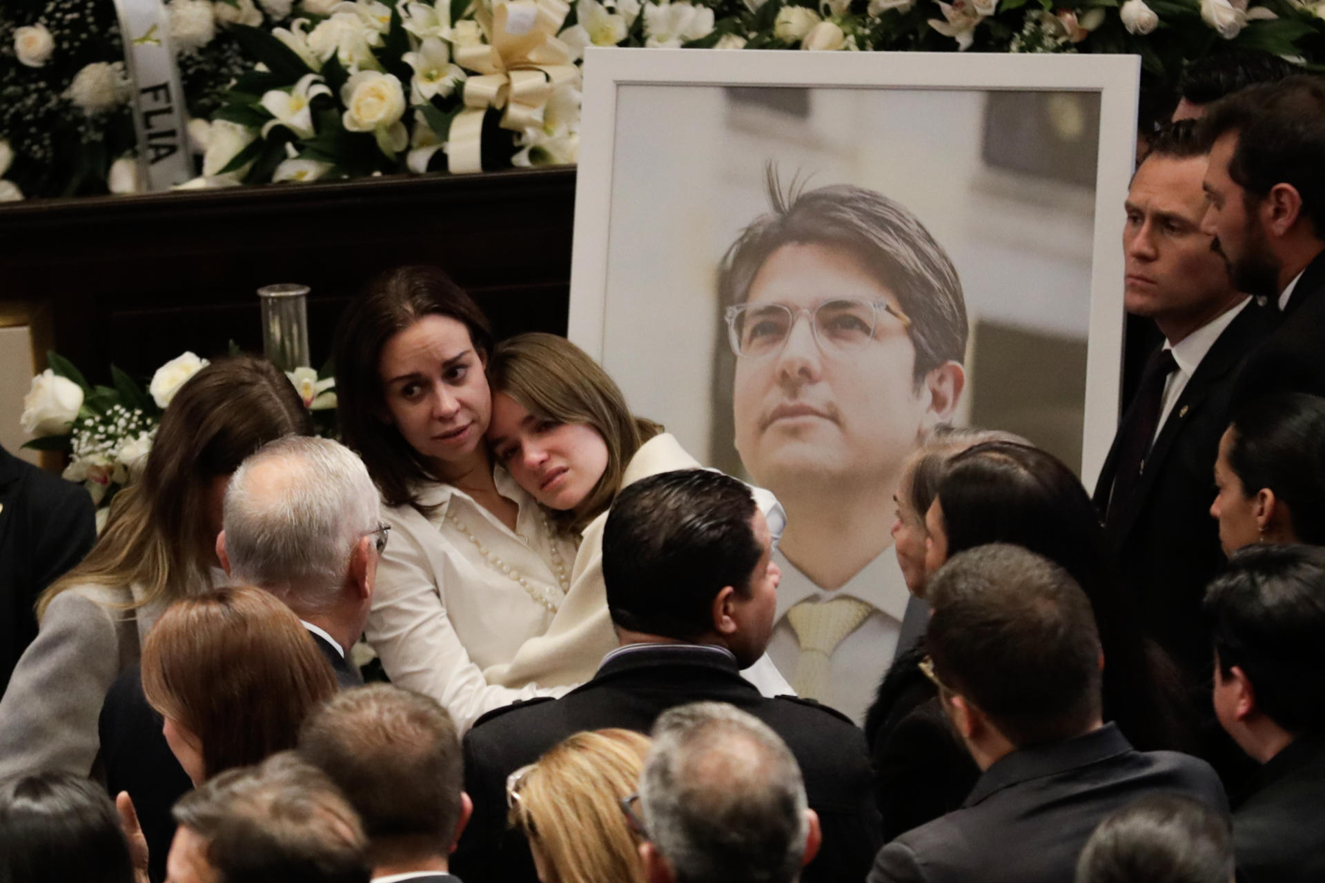 AME9307. BOGOTÁ (COLOMBIA), 11/08/2025.- La esposa del fallecido senador y precandidato a la presidencia de Colombia Miguel Uribe Turbay, Claudia Tarazona (c-i), abraza a una de sus hijas frente a una fotografía de Miguel este lunes, en el Salón Elíptico del Capitolio Nacional en Bogotá (Colombia). Uribe Turbay falleció después de ser gravemente herido en un atentado hace 64 días. EFE/ Carlos Ortega