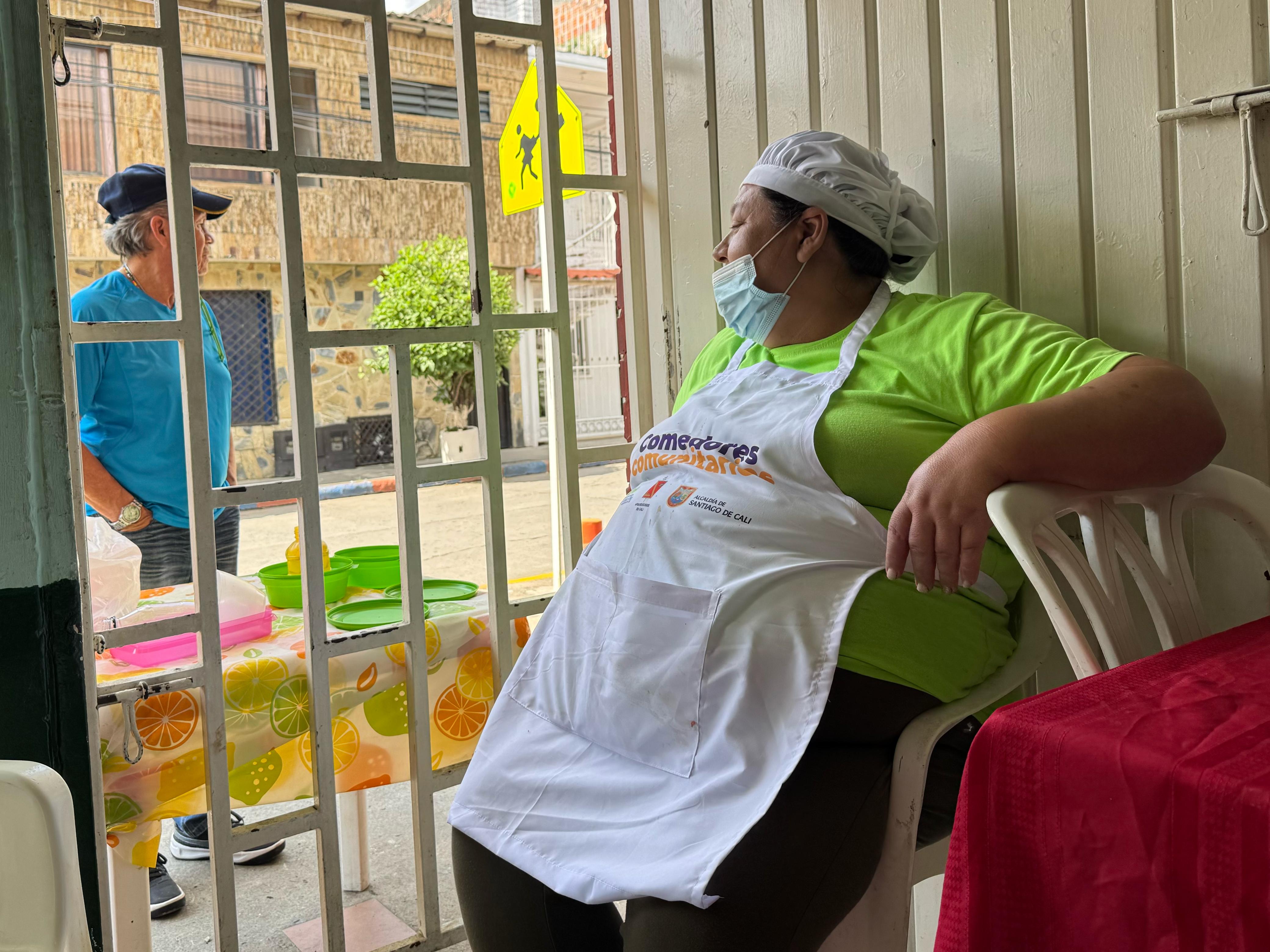 Lucy Uribe, tras terminar de cocinar el almuerzo, se sienta a atender a los clientes que piden el almuerzo para llevar a través de una rendija.