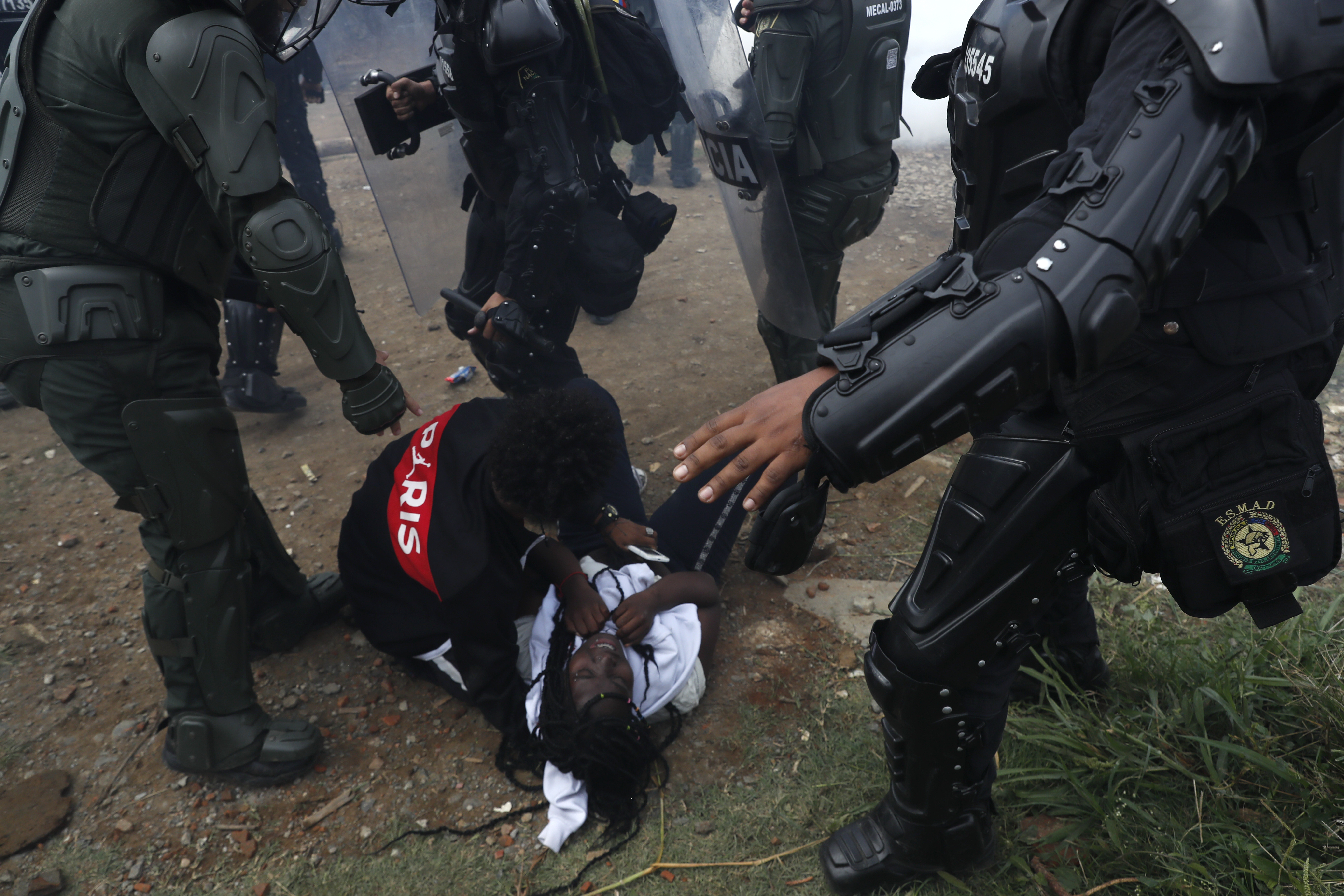 AME2592. CALI (COLOMBIA), 06/10/2022.- Un hombre ayuda hoy a una mujer tras choques con policías antidisturbios, durante el desalojo de un predio invadido por 1.500 familias, en el corregimiento Navarro en Cali (Colombia). El desalojo de unas 1.500 familias en el oriente de Cali, en una de las zonas de "invasión" más grandes de esa ciudad colombiana, provocó momentos de tensión este jueves entre los vecinos del asentamiento y las autoridades locales y fuerzas de seguridad. EFE/ Ernesto Guzmán