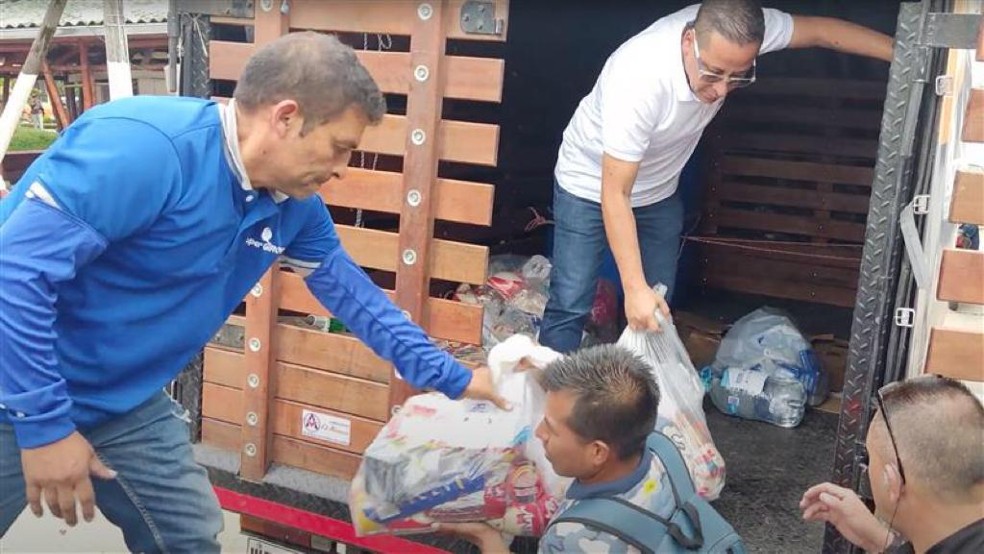 Voluntarios bajan de un camión los paquetes con ayudas para los damnificados en Roas (Cauca)