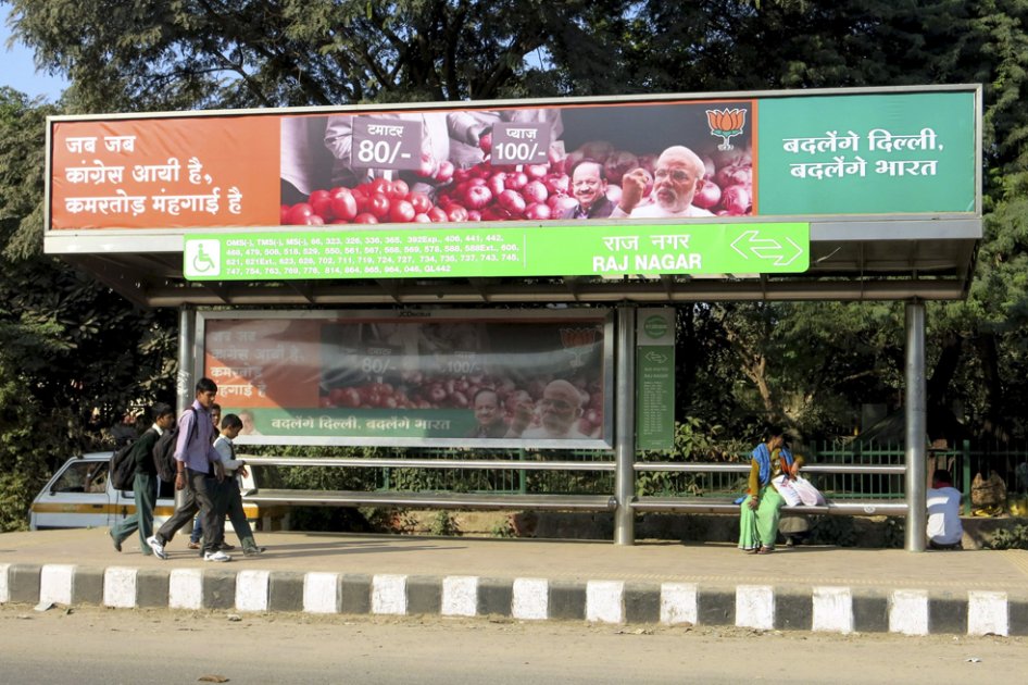 Un cartel de Narendra Modi, el candidato a primer ministro del BJP, denunciando los precios y mostrando cebollas y tomates a los transeúntes, en una parada de autobús en la capital Nueva Delhi./ EFE