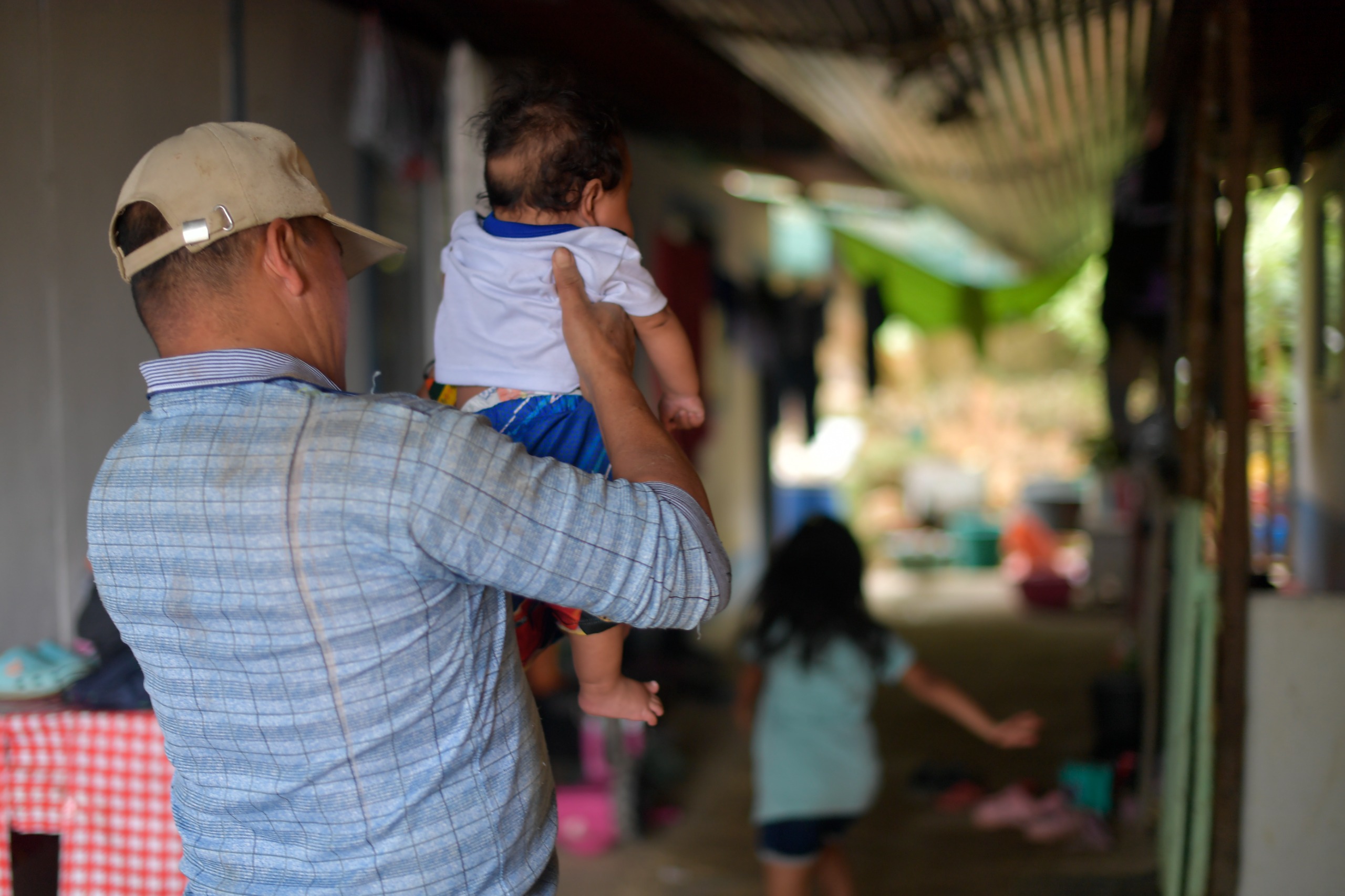 Segundo carga a su bebé mientras Evelin, su hija mayor, juega en los pasillos del ETCR.