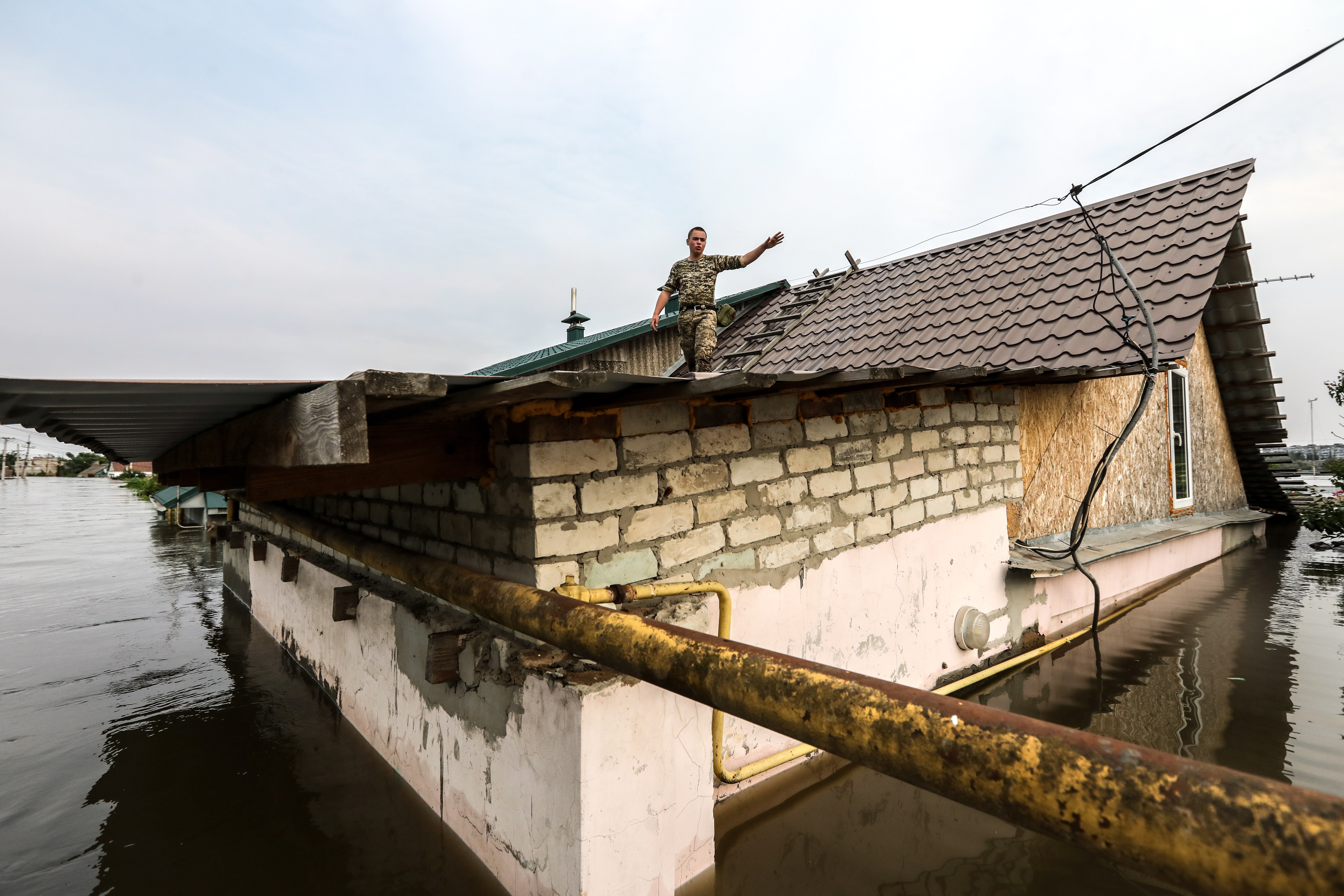 Kherson (Ukraine), 07/06/2023.- A man gestures from the roof of a house surrounded by flood water in Kherson, Ukraine, 07 June 2023. Ukraine has accused Russian forces of destroying a critical dam and hydroelectric power plant on the Dnipro River in the Kherson region along the front line in southern Ukraine on 06 June. A number of settlements were completely or partially flooded, Kherson region governor Oleksandr Prokudin said on telegram. Russian troops entered Ukraine in February 2022 starting a conflict that has provoked destruction and a humanitarian crisis. (Rusia, Ucrania) EFE/EPA/MYKOLA TYMCHENKO