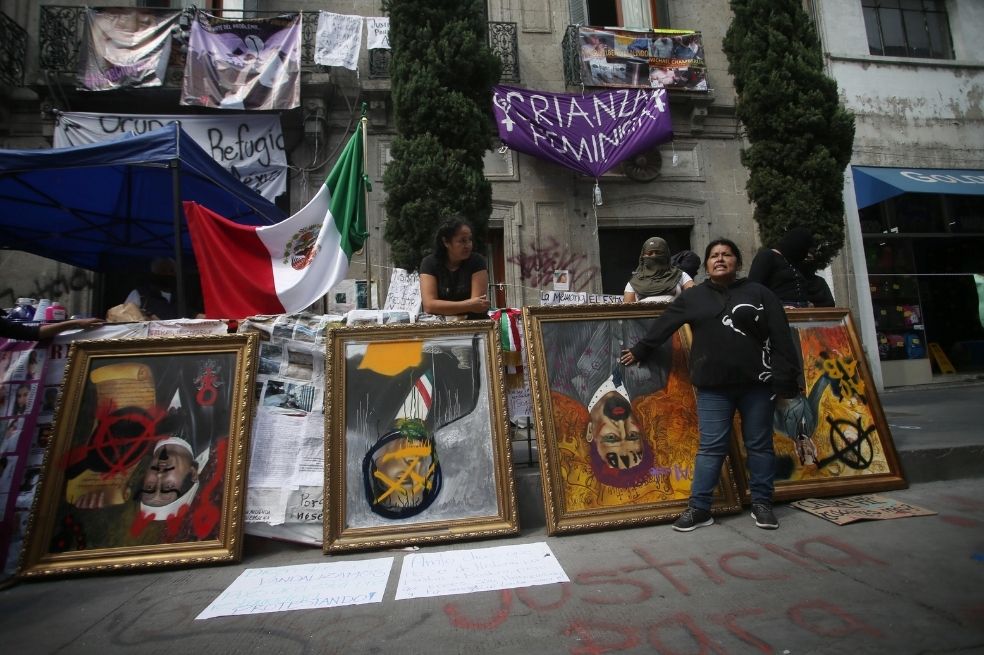 Una mujer muestra cuadros intervenidos y denuncia los abusos que han sufrido sus familiares y la falta de justicia a las afueras de las instalaciones de la Comisión Nacional de Derechos Humanos en Ciudad de México (México).