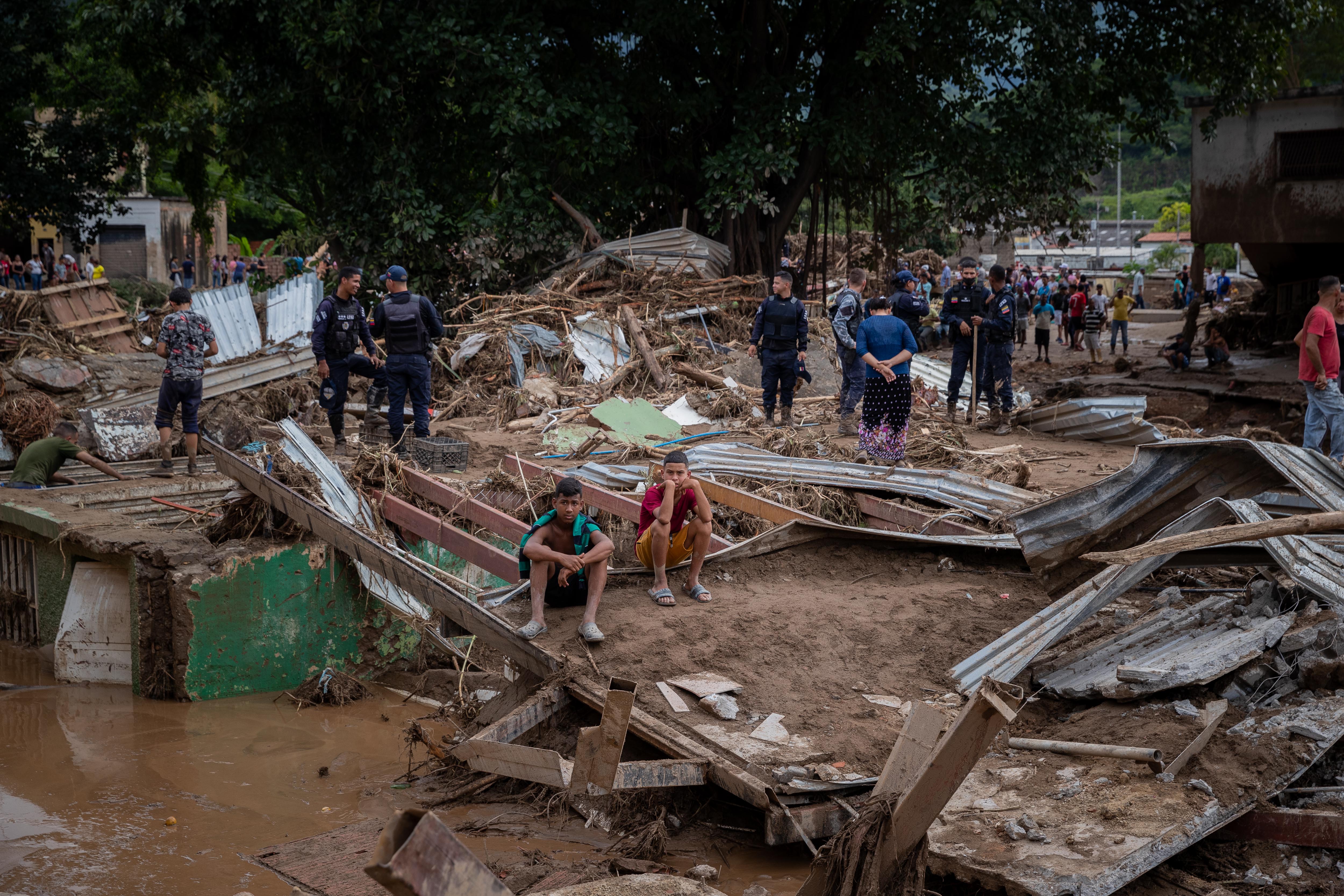 AME3286. TEJERIAS (VENEZUELA), 09/10/2022.- Habitantes de los alrededores de la quebrada (rio) Los Patos, estado Aragua, observan las inundaciones en Tejerías (Venezuela). La crecida de una quebrada este sábado arrastró viviendas, mobiliario urbano, e inundó las calles de la localidad, arrasando con todo lo que el agua encontró a su paso. El Gobierno desplegó hoy organismos de salvamento, seguridad ciudadana, así como cuadrillas de mantenimiento y limpieza, y personal de diversas instituciones para "la atención integral del pueblo", dijo el presidente Nicolás Maduro a través de su cuenta de Twitter.EFE/ Rayner Peña R.