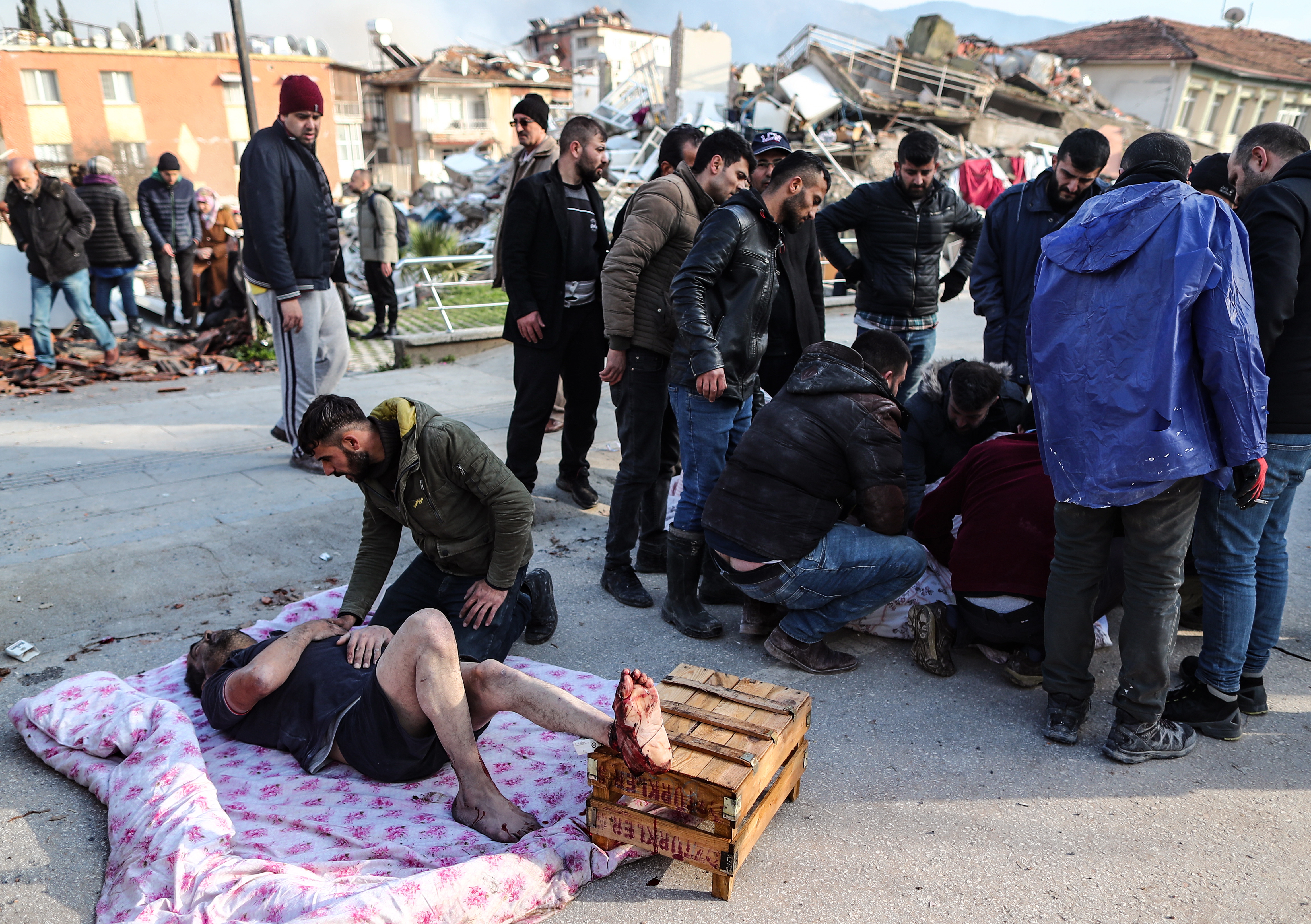 Hatay (Turkey), 07/02/2023.- People help wounded people on the ground near a collapsed building in Hatay, Turkey, 07 February 2023. Thousands of people died thousands more were injured after major earthquakes struck southern Turkey and northern Syria on 06 February. Authorities fear the death toll will keep climbing as rescuers look for survivors across the region. (Terremoto/sismo, Siria, Turquía, Estados Unidos) EFE/EPA/ERDEM SAHIN