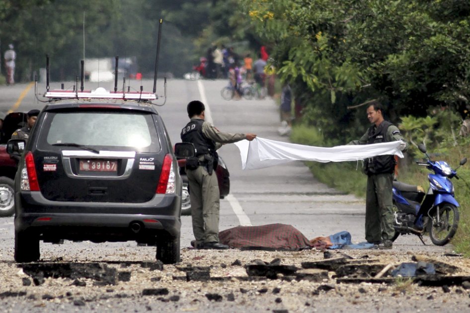 Dos agentes de policía cubren el cadáver de un acompañero tras resultar muerto durante la detonación de un artefacto explosivo que trataban de desactivar en la provincia de mayoría musulmana de Narathiwat, al sur de Tailandia./ EFE