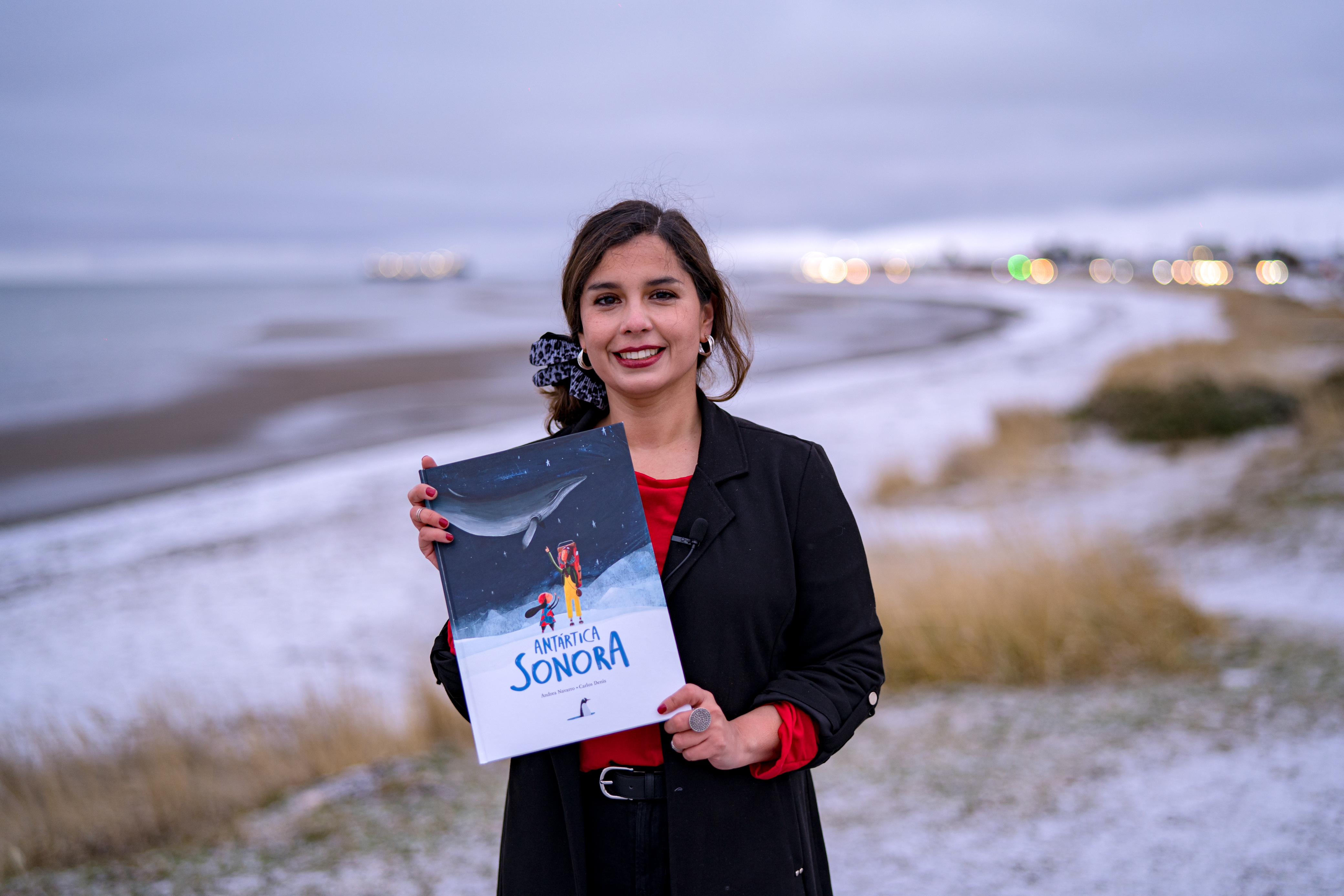 AME2016. PUNTA ARENAS (CHILE), 20/08/2024.- Fotografía sin fechar cedida por la Universidad Austral de Chile de la escritora y periodista Andrea Navarro posando junto al libro de su autoría, "Antártica Sonora", en la ciudad de Punta Arenas (Chile). Concebido como un proyecto de divulgación científica internacional que conecta la acústica marina, la literatura y el arte, este martes fue lanzado en Chile el libro "Antártica Sonora", una publicación que "ofrece una experiencia inmersiva" a través de códigos QR integrados en sus páginas, donde los lectores podrán acceder a registros acústicos auténticos de ballenas, focas y pingüinos, entre otras especies de llamado continente blanco. EFE/ UNIVERSIDAD AUSTRAL DE CHILE /SOLO USO EDITORIAL/SOLO DISPONIBLE PARA ILUSTRAR LA NOTICIA QUE ACOMPAÑA (CRÉDITO OBLIGATORIO)