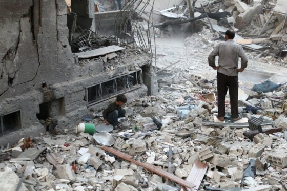 Un niño escarba entre los restos que dejó un bombardeo registrado en octubre pasado en Douma, en las afueras de Damasco (capital de Siria). /EFE