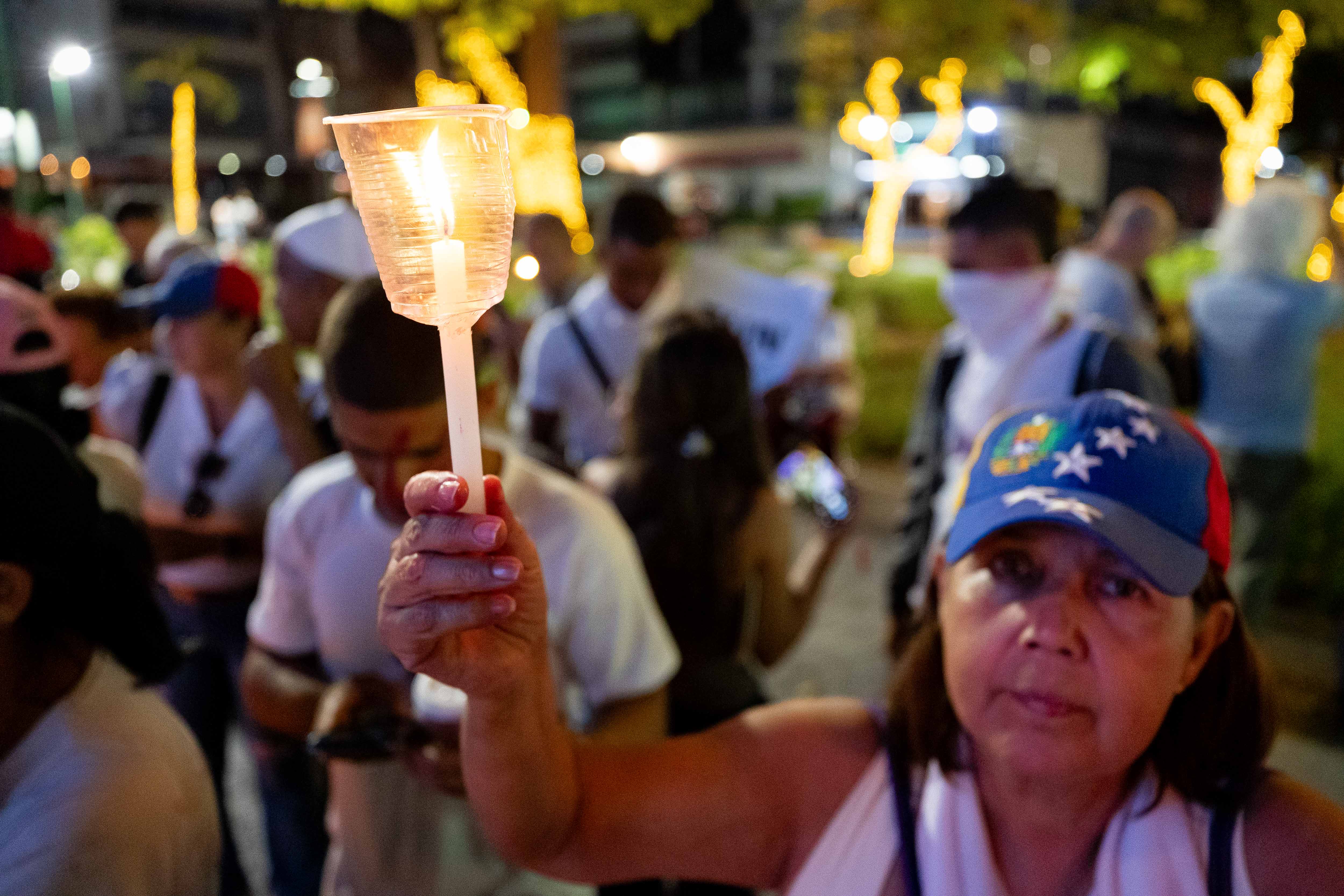 AME2597. CARACAS (VENEZUELA), 01/12/2024.- Una mujer sostiene una vela durante una vigilia este domingo, en Caracas (Venezuela). Familiares y amigos de los considerados "presos políticos", acompañados de activistas y otros ciudadanos, llevaron a cabo una vigilia en una plaza de Caracas para exigir la liberación de estos detenidos, así como el "cese de la represión" en el país. EFE/ Ronald Peña