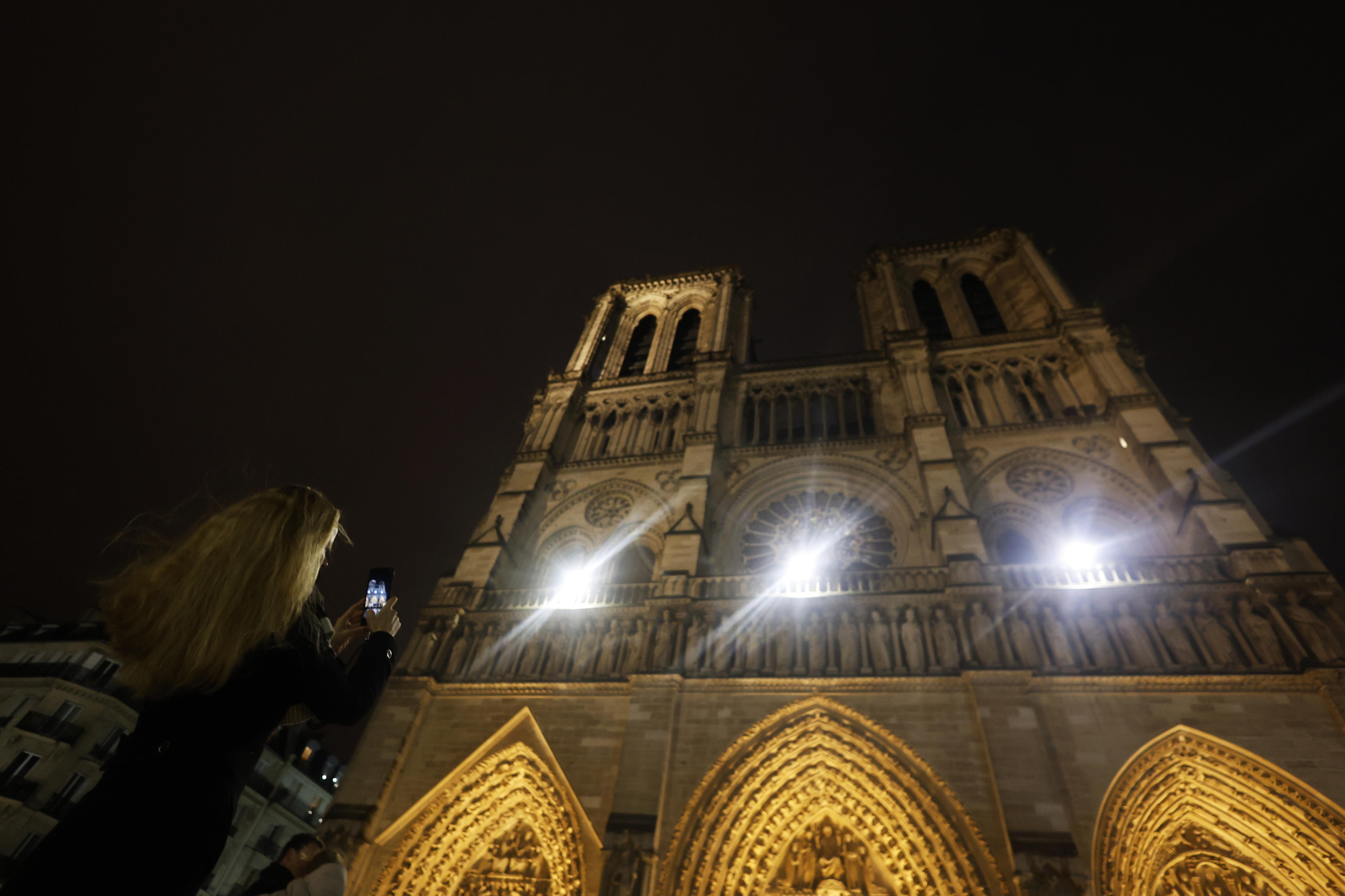 Paris (France), 08/12/2024.- A woman takes pictures of the Notre-Dame de Paris cathedral before the start of the first mass open to the public in Paris, France, 08 December 2024. About 2,500 people are expected to attend this reserved event. The Notre Dame de Paris Cathedral reopened on 07 December after nearly six years of renovation work following its destruction by a fire on 15 April 2019. (Francia) EFE/EPA/MOHAMMED BADRA