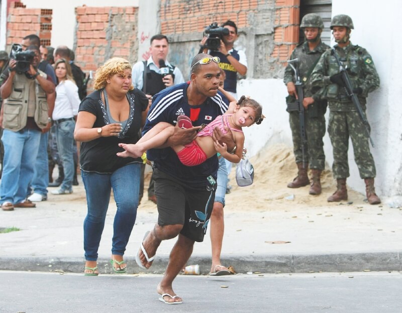  Civiles corren en medio de un enfrentamiento entre soldados brasileños y bandas narcotraficantes. / EFE