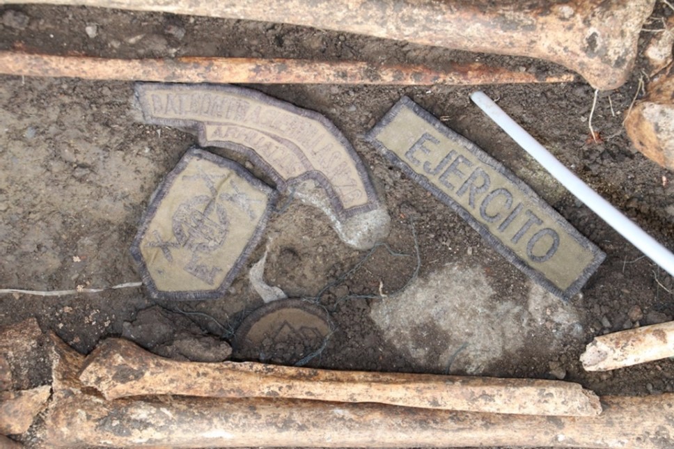 Luego de que la testigo señaló dónde había visto un montículo de tierra, las autoridades encontraron esta fosa con los restos de una de las víctimas de ejecuciones extrajudiciales y las insignias del batallón del Ejército que perpetró el asesinato.