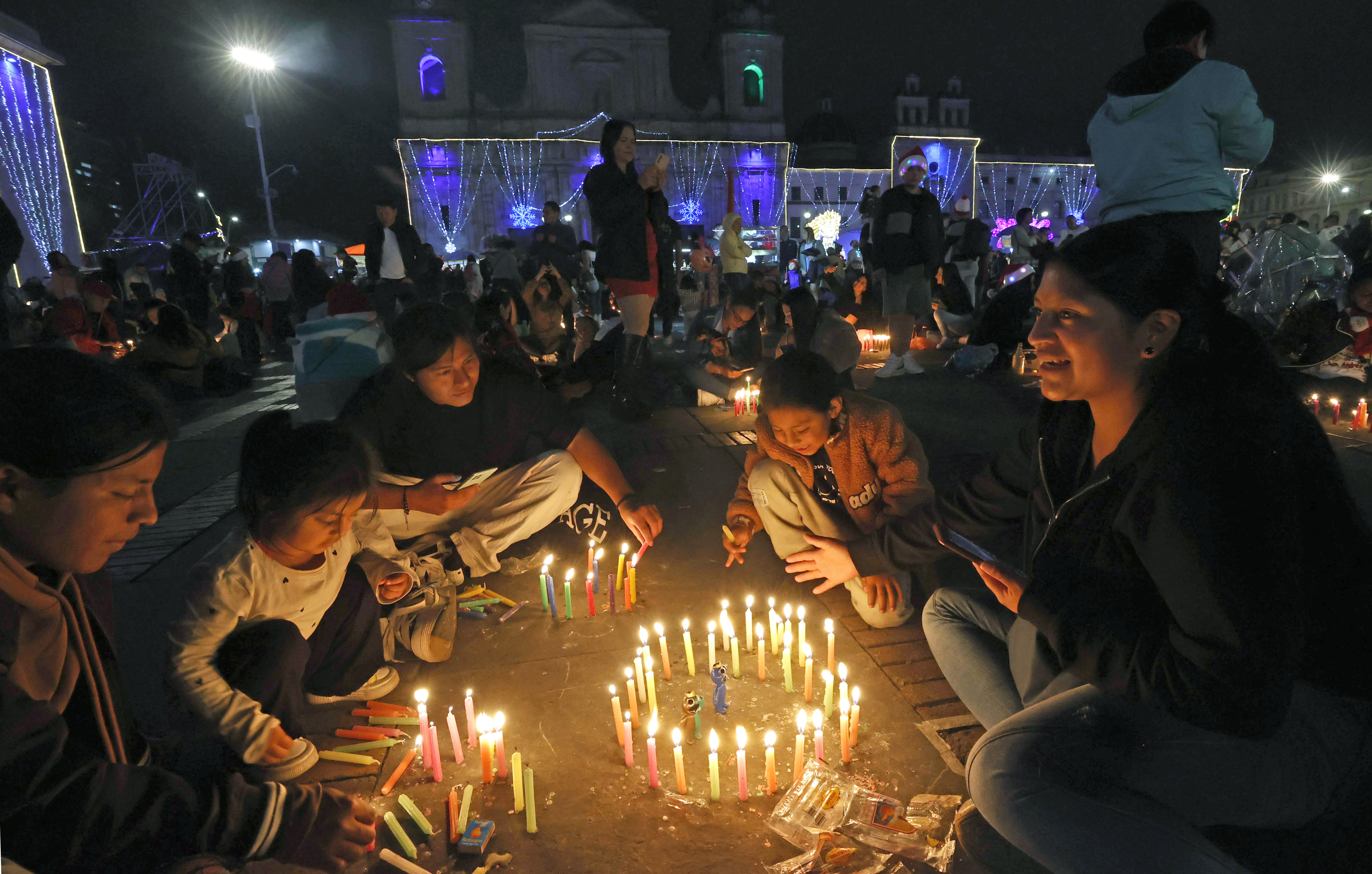 AME4042. BOGOTÁ (COLOMBIA), 07/12/2024.- Personas encienden velas durante la tradicional Noche de las Velitas este sábado en Bogotá (Colombia). La tradicional Noche de las Velitas, que marca el inicio de la Navidad en Colombia, se vivió este sábado en el que familias a lo largo y ancho del país se reunieron en viviendas, edificios, plazas y parques para compartir comida y golosinas y disfrutar de los alumbrados navideños. EFE/Mauricio Dueñas Castañeda