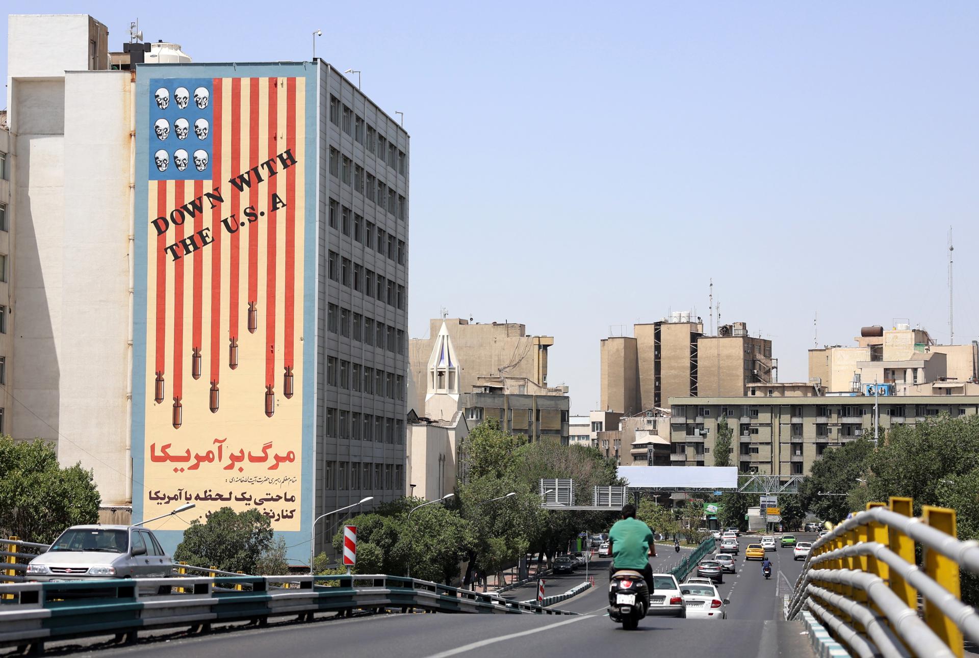 FOTODELDIA Teherán (República Islámica de Irán), 22/06/2025.- Tráfico junto a un edificio con un mural antiestadounidense en Teherán, Irán, el 22 de junio de 2025. Las fuerzas estadounidenses atacaron tres de las principales instalaciones nucleares de Irán: Natanz, Isfahán y Fordo, según anunció el presidente estadounidense Trump el 21 de junio. Israel e Irán han estado intercambiando disparos desde que Israel lanzó ataques en Irán el 13 de junio de 2025 como parte de la Operación "León Ascendente". EFE/EPA/ABEDIN TAHERKENAREH