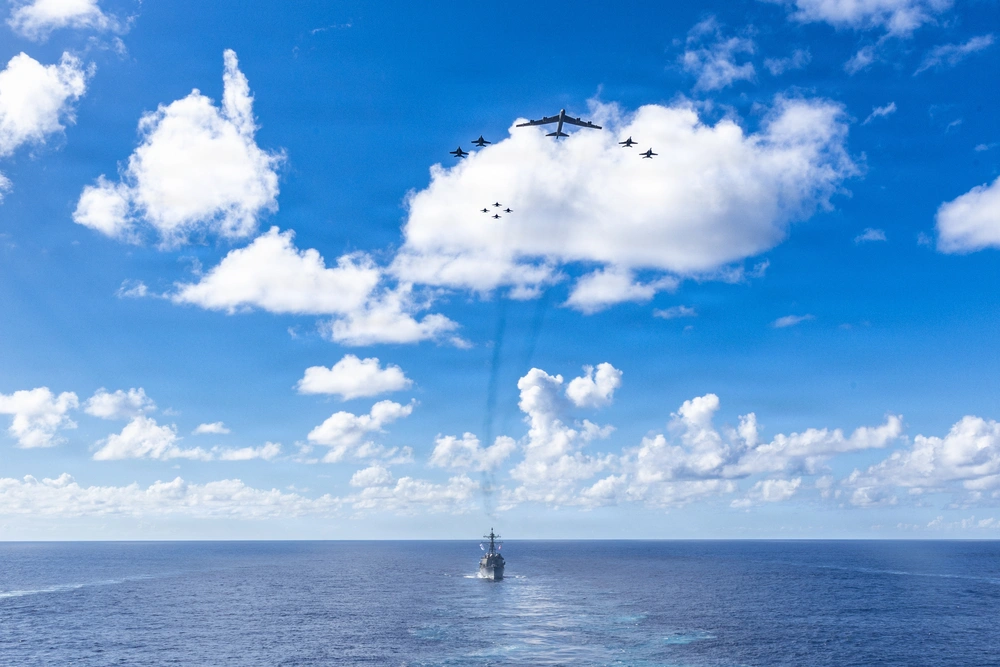 En el agua, uno de los destructores de misiles que escoltan al USS Gerald Ford; en el cielo, unidades del portaaviones y el bombardero B-52.