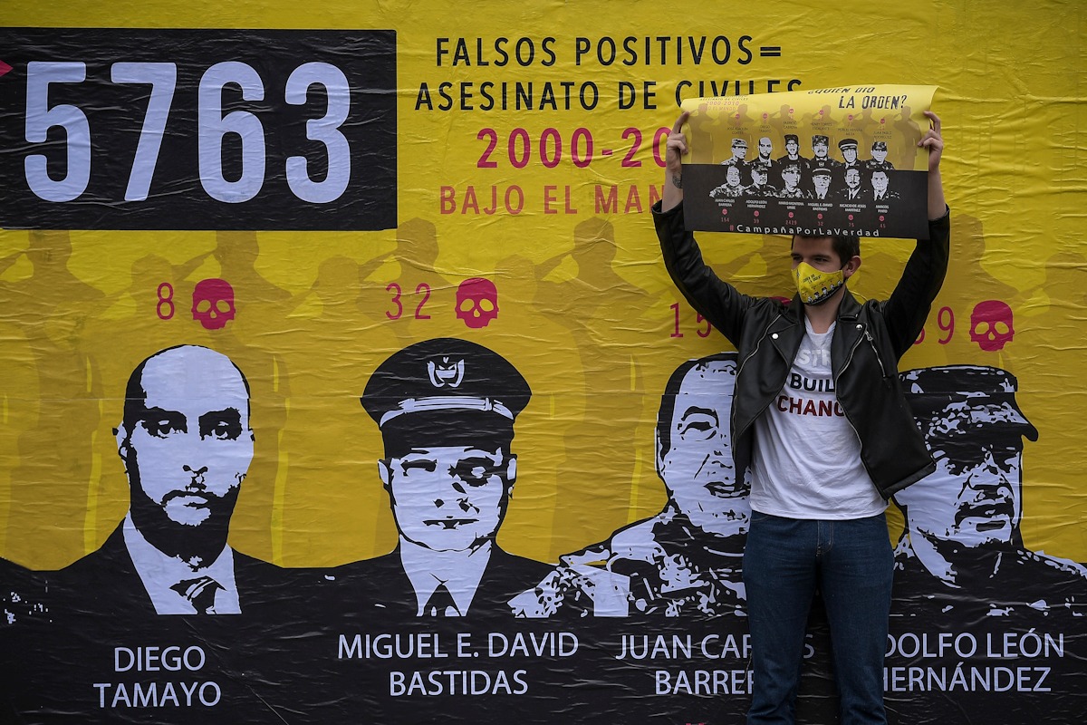 Un hombre sostiene un cartel con el retrato de varios militares investigados por falsos positivos.