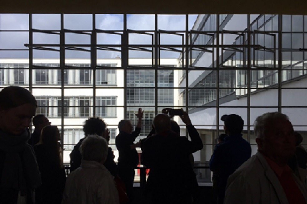 Figura 1: Turistas en la sede de Bauhaus en Dessau (Walter Gropius).Virginia Gutiérrez, 2019.Hace un año, cuando aun se convocaban romerías, Alemania lanzó una intensa agenda cultural en torno al centenario de Bauhaus, Repentinamente, ese pasó de ser término exclusivo de iniciados para convertirse en una marca desde la cual se impulsó un turismo de masas a través de las primeras realizaciones arquitectónicas de la escuela –episodio inédito en regiones germánicas como Turingia y Sajonia (figura 1)--. Además, la fiebre del centenario inspiró producciones audiovisuales, un sinnúmero de exposiciones y jornadas académicas a lo largo de Europa, Asia y las Américas, en las que se homenajeó la visita de alguno de sus maestros a sus respectivas latitudes o su impacto en el desarrollo de estéticas materiales locales. Pese a no haber contado con nacionales egresados de Bauhaus, Colombia no fue ajena a las conmemoraciones: la Universidad Jorge Tadeo Lozano organizó un seminario académico, el portal web AD57 promovió un ciclo de conferencias bajo el título “Bauhaus 100 Colombia” y la Universidad Nacional de Colombia presentó su propia versión del Ballet Triádico, emblemática puesta en escena interdisciplinar lanzada en 1922 por Oskar Schlemmer.