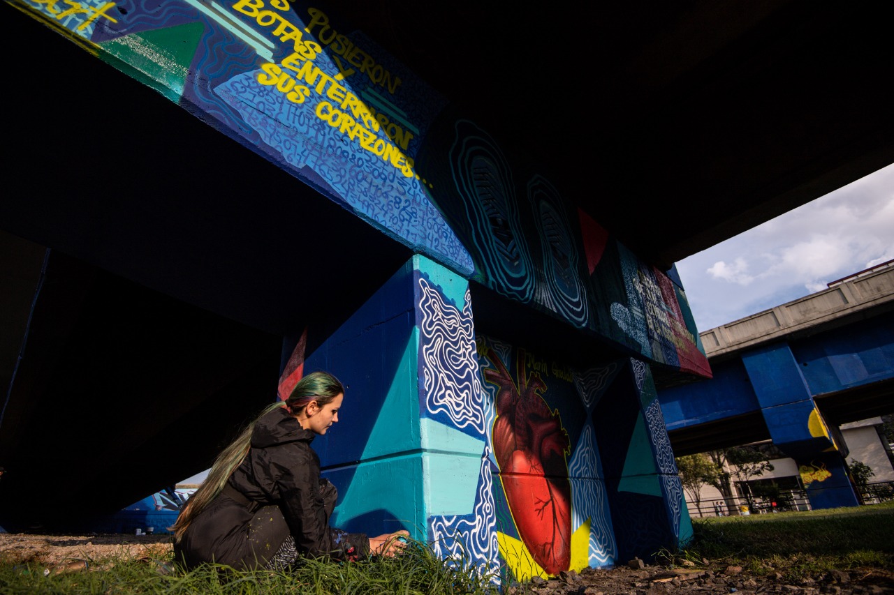 Una mujer pinta un grafiti en una pared.