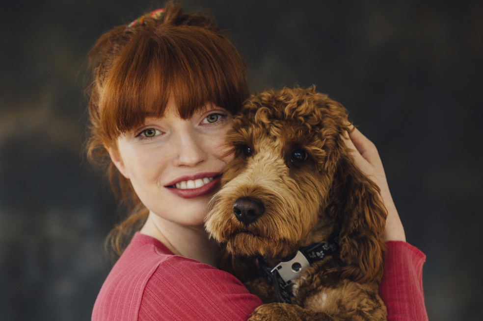 Woman posing with her pet dog in her arms.