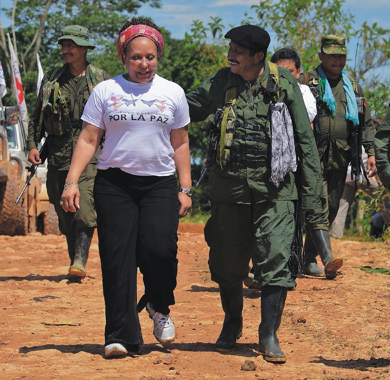 Revolutionary Armed Forces of Colombia (FARC) guerrilla commander, Jairo (C), walks with Colombian former senator Piedad Cordoba (L) in San Isidro, in the Colombian southern department of Caqueta, on May 30, 2012 as the humanitarian mission waits for the release of French journalist Romeo Langlois, held by the rebels for more than a month. France 24 reporter Romeo Langlois was captured at the end of April by FARC rebels during an attack on a Colombian army unit he was embedded with to film a counter-drug operation. AFP PHOTO/Luis ACOSTA