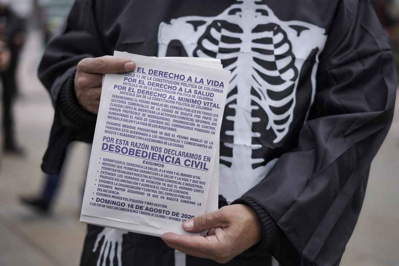 Hombre disfrazado de calavera sostiene una hoja con las solicitudes al Distrito.