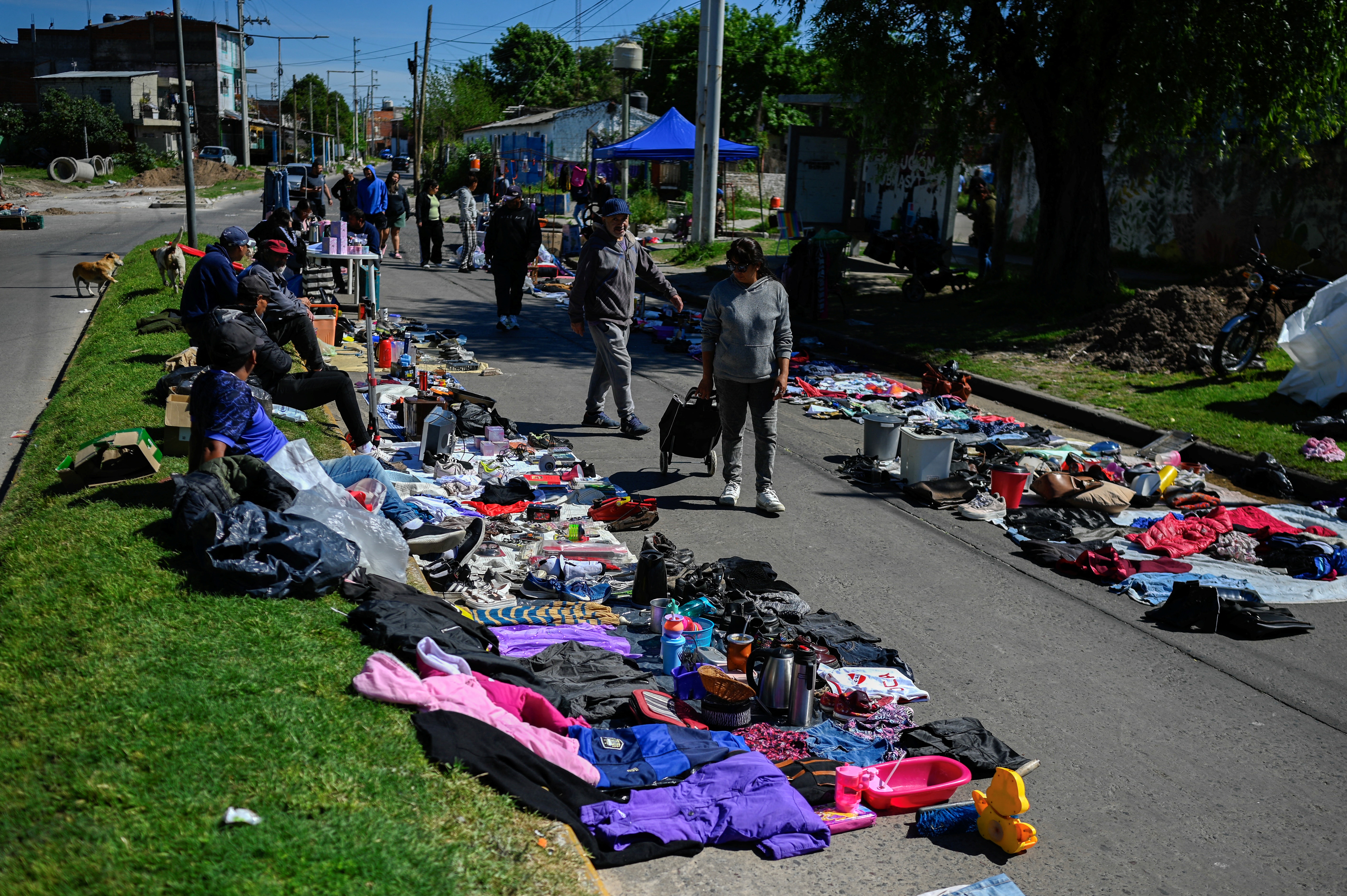 People walk through a street market in Villa Fiorito, on the outskirts of Buenos Aires, on October 19, 2025. The street market in the neighborhood where Diego Maradona was born keeps growing: more and more residents are selling what they have � or what they find on the street � to survive, amid a deepening economic crisis in Argentina on the eve of the elections. (Photo by Luis ROBAYO / AFP)
