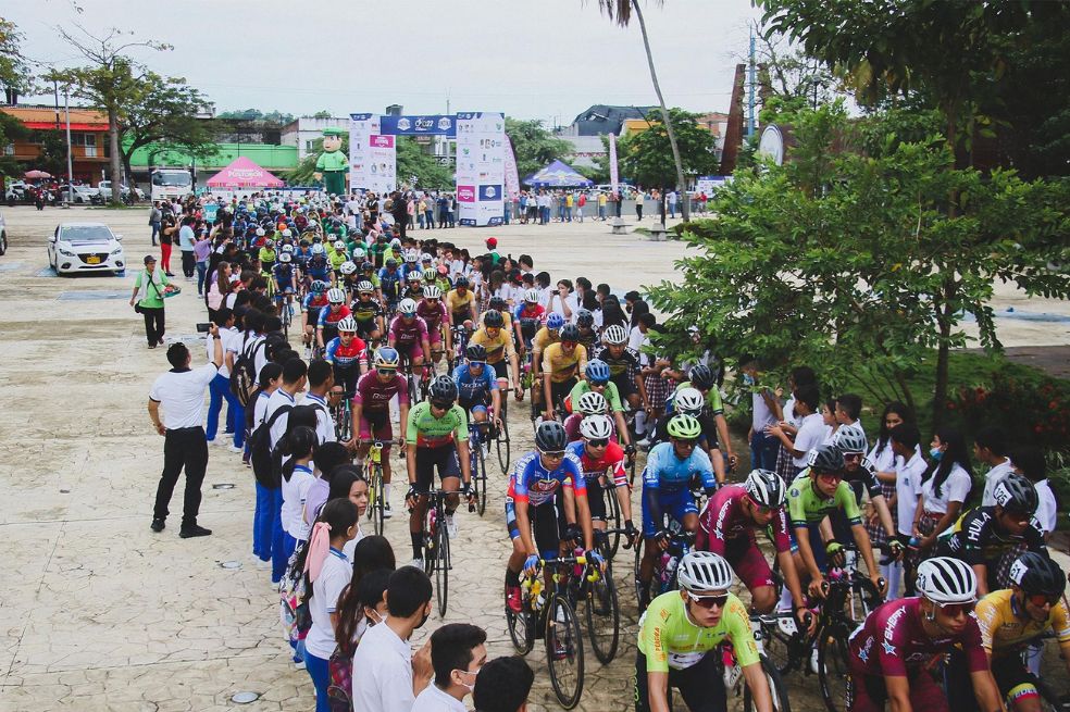 El pelotón del Clásico RCN deja Puerto Boyacá ante el pasillo de los niños del pueblo. Atrás el obelisco en memoria de las víctimas de las AUC.