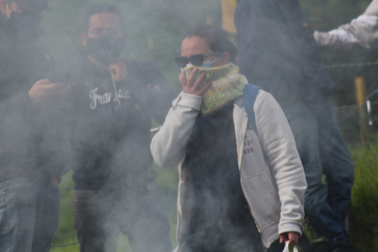 Una mujer con una mano en la boca protegiéndose de los gases.