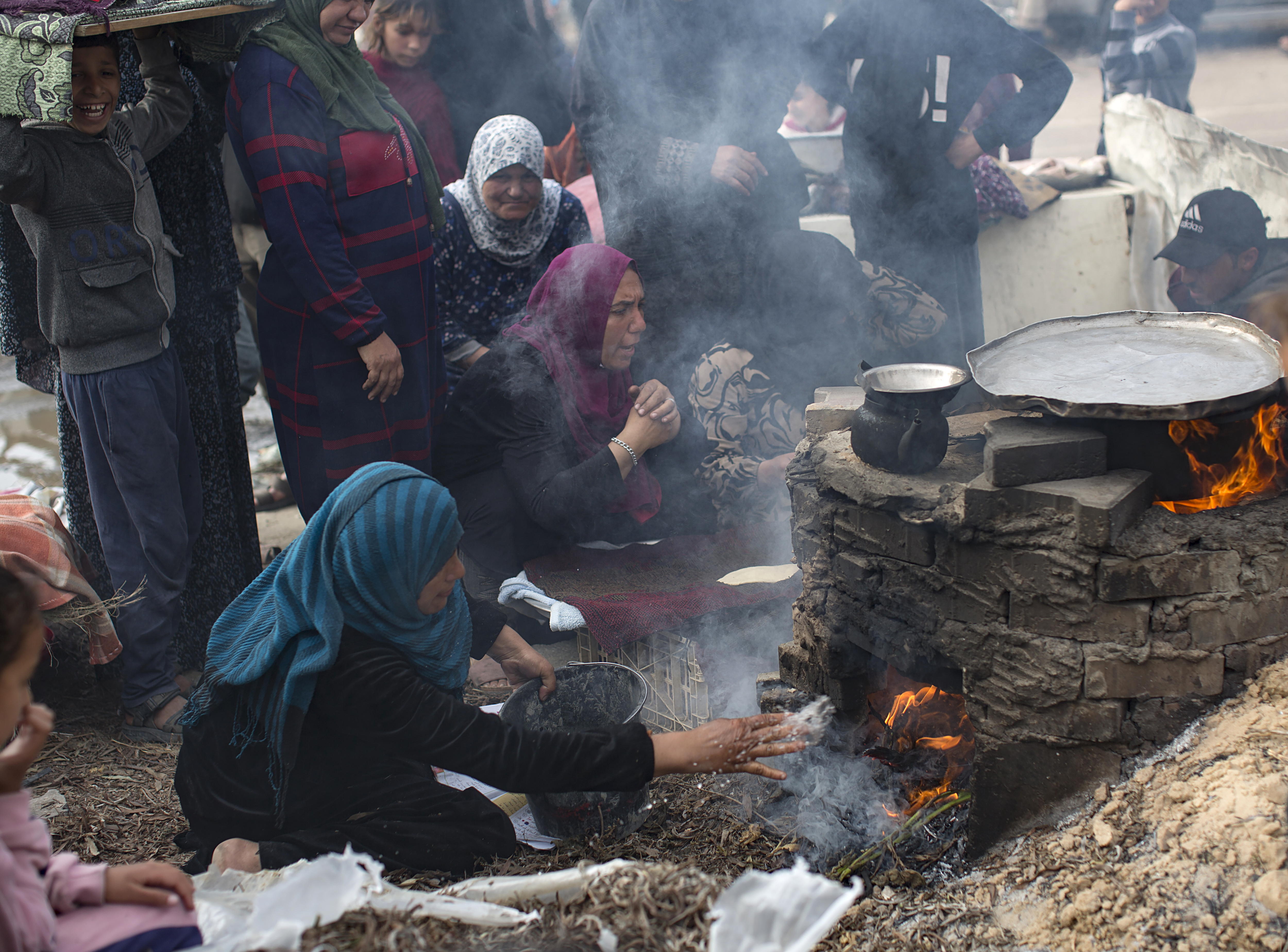 -FOTODELDÍA- RAFAH (PALESTINA), 23/12/2023.- Familias palestinas desplazadas hacen pan en un horno de leña debido a la ausencia de gas en un campo de refugiados en Rafah, en las Franja de Gaza, este sábado. El número de víctimas en la Franja de Gaza subió a 20.258 muertos y 53.688 heridos desde que estalló la guerra el 7 de octubre entre el grupo islamista Hamás e Israel, informaron este sábado las autoridades sanitarias del enclave palestino. EFE/ Haitham Imad