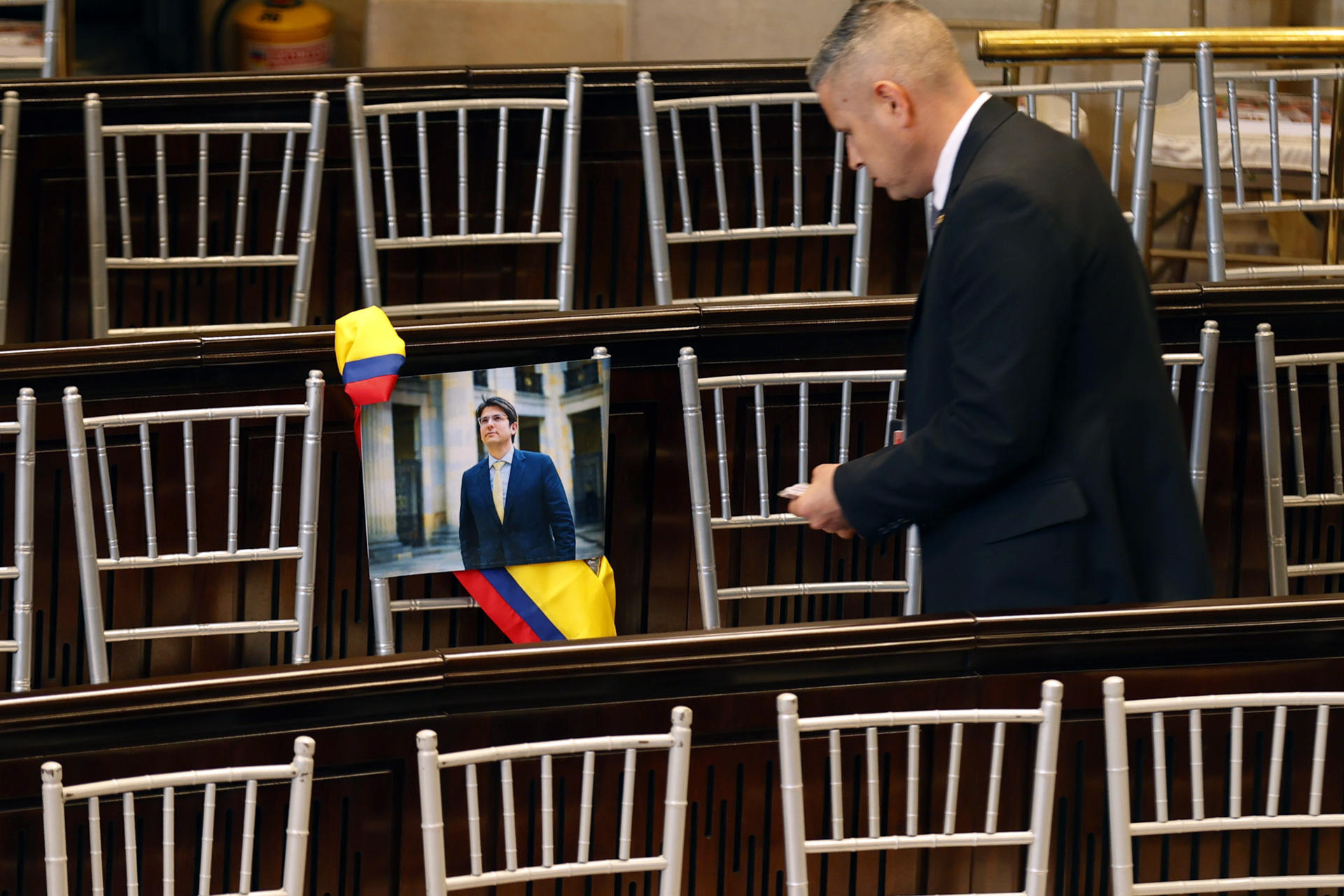 AME4160. BOGOTÁ (COLOMBIA), 20/07/2025.- Una persona observa una fotografía del senador Miguel Uribe puesta en una silla durante la instalación del nuevo periodo de sesiones del Congreso este domingo, en Bogotá (Colombia). Petro destacó ante el Congreso los avances económicos que ha conseguido en sus primeros tres años de Gobierno pero reconoció que no ha logrado sacar adelante la política de "paz total" con los grupos armados, una de sus grandes promesas de campaña. EFE/ Mauricio Dueñas Castañeda