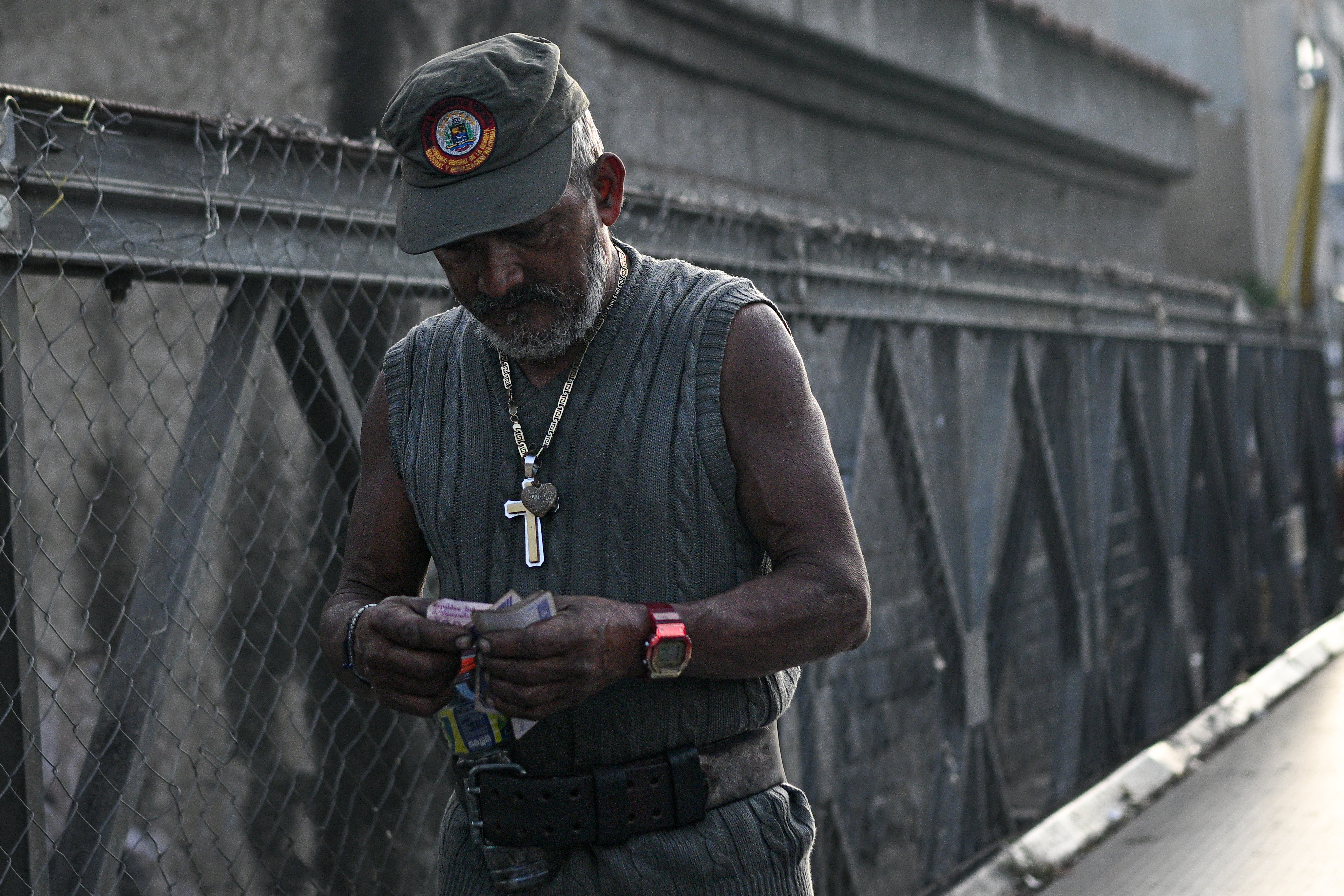 A man counts Venezuelan bolivar bills to buy food at the Quinta Crespo market in Caracas on September 30, 2025. The Venezuelan currency closed September 2025 with a 71% drop against the dollar since January 2, to the distress of millions of families surviving the world's highest inflation, projected by the IMF at 254% by the end of 2025. (Photo by Federico PARRA / AFP)