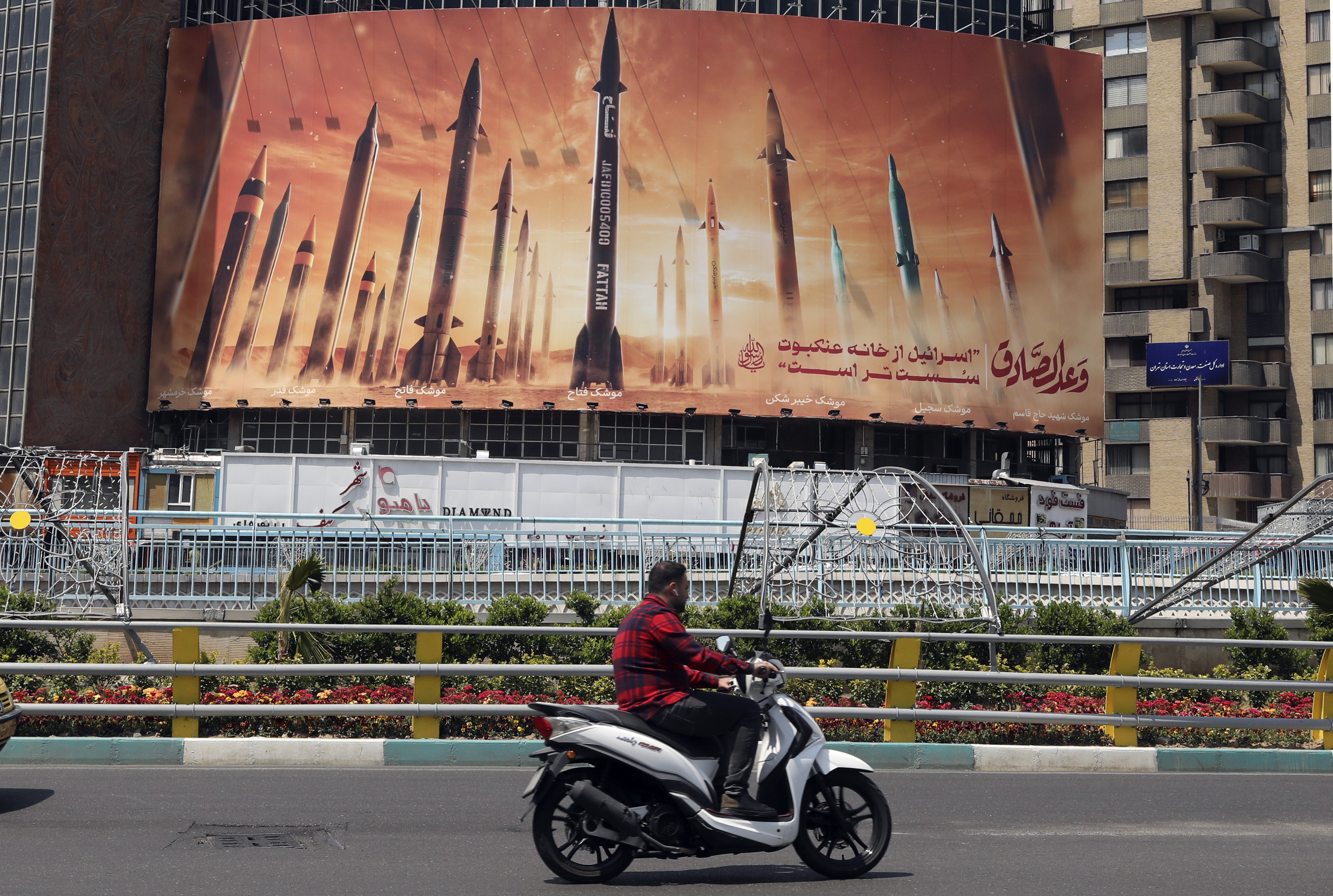 Tehran (Iran (islamic Republic Of)), 15/04/2024.- A man drives past an anti-Israel billboard carrying pictures of Iranian missiles in Tehran, Iran, 15 April 2024. Iran's Islamic Revolutionary Guards Corps (IRGC) launched drones and rockets towards Israel late on 13 April 2024, Iranian officials said. (Teherán) EFE/EPA/ABEDIN TAHERKENAREH