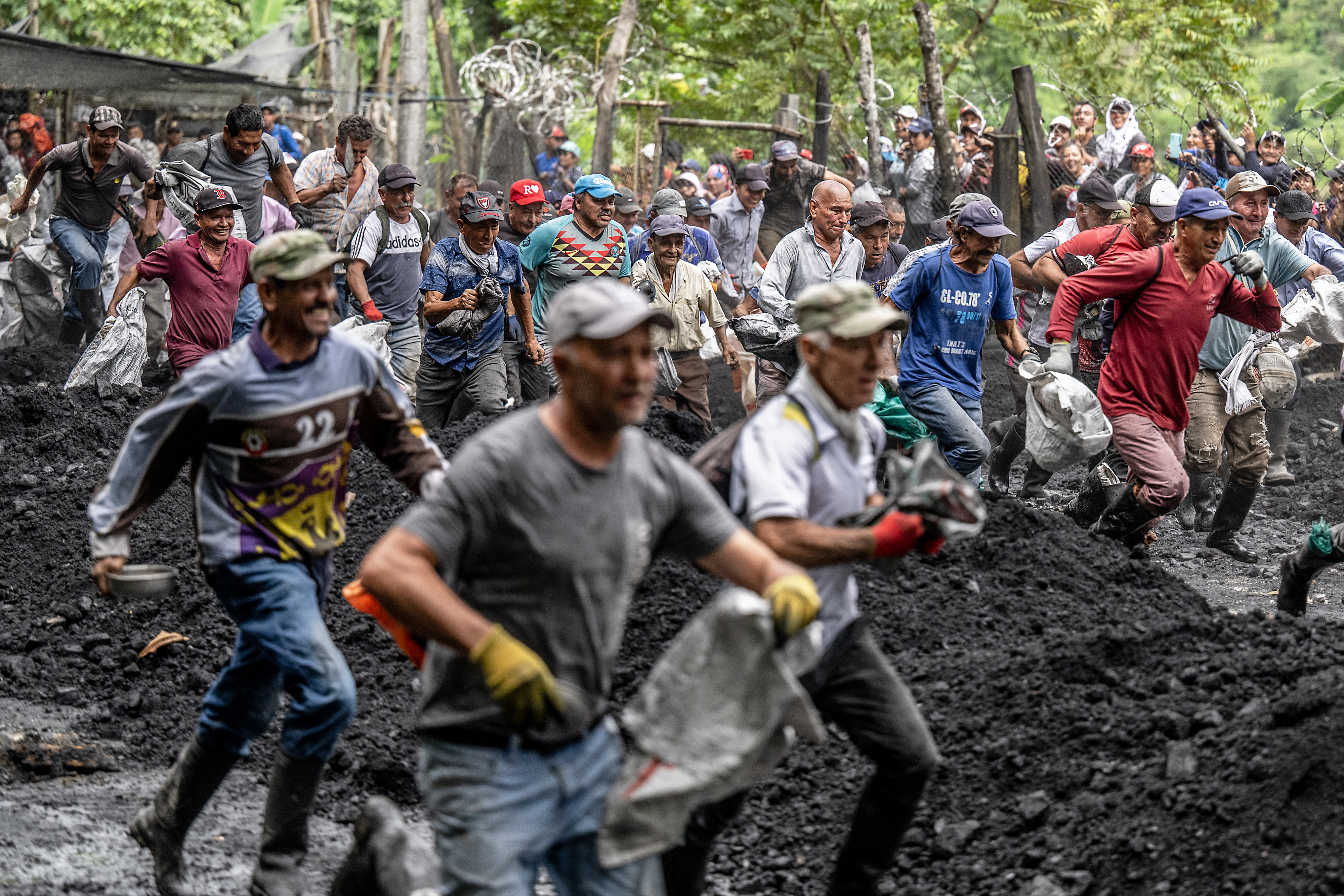 Emerald seekers run after entering 'La Voladora,' a cage where the multinational Esmeraldas Mining Services (EMS) leaves tons of soil discarded from its production, to search for green gems at the Las Animas River in Muzo, Boyaca Department, Colombia, on June 19, 2024.