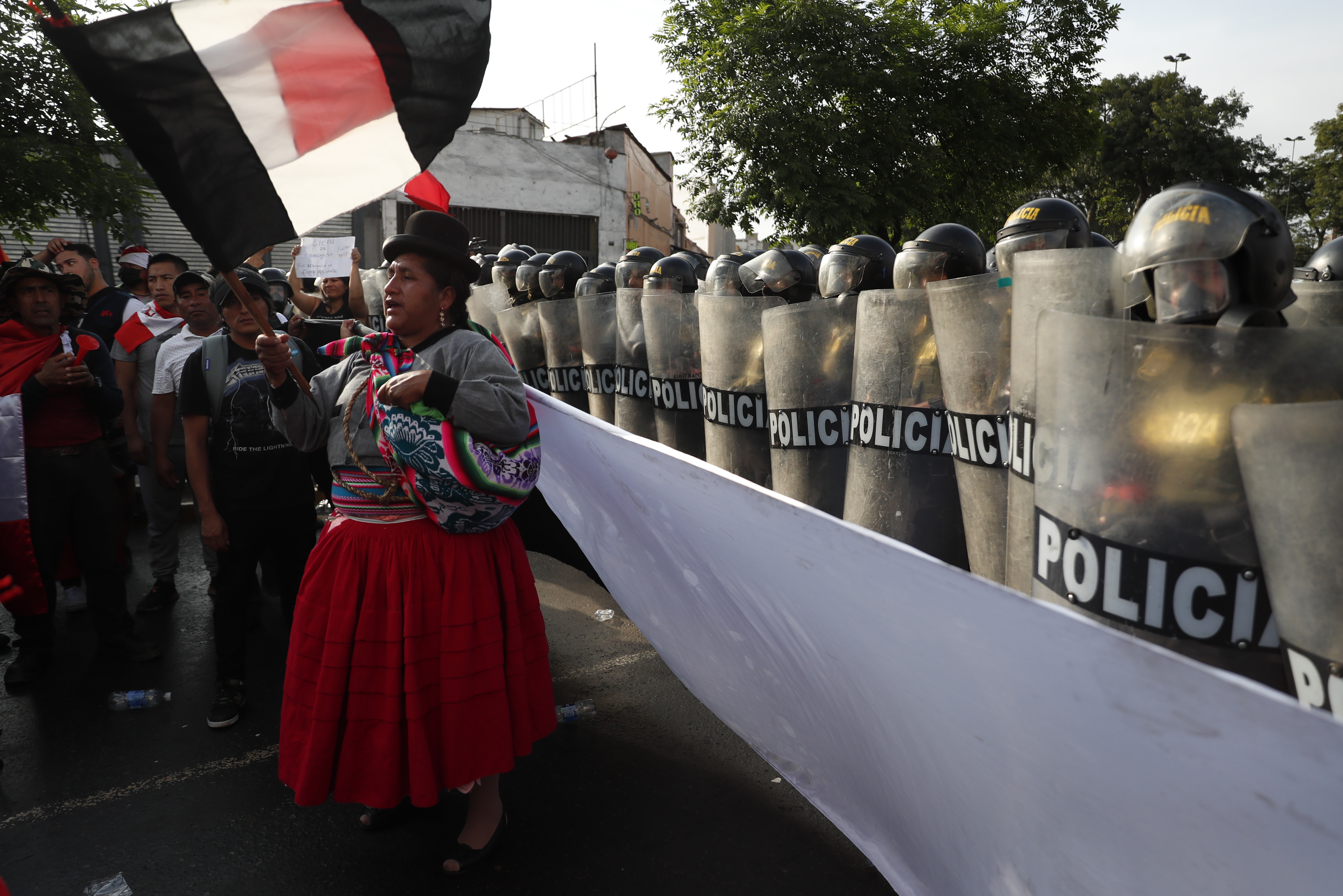 AME7303. LIMA (PERÚ), 19/01/2023.- Una mujer participa en la marcha llamada la "toma de Lima" mientras miembros de la policía montan guardia hoy, en Lima (Perú). La gran marcha nacional denominada "la toma de Lima" ha activado una serie de acciones de protesta en distintos puntos del país, en donde los manifestantes exigen la renuncia de la presidenta Dina Boluarte y el cierre del Congreso, así como la convocatoria a elecciones generales para este año y a una asamblea constituyente. Las manifestaciones en Perú comenzaron el 7 de diciembre pasado, cuando Boluarte asumió la Presidencia por sucesión constitucional tras el fallido autogolpe de Castillo (2021-2022) y, luego de una tregua navideña, volvieron a cobrar fuerza a partir del 4 de enero, sobre todo en el sur. EFE/ Paolo Aguilar