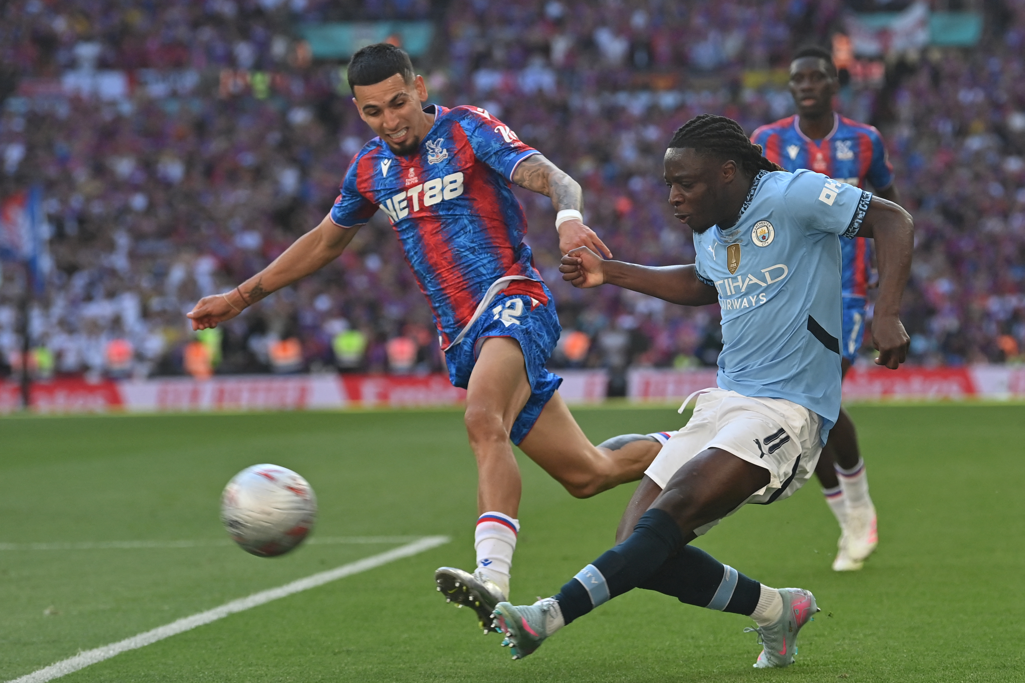 El colombiano Daniel Muñoz (izq.), lateral derecho del Crystal Palace, lucha una pelota con el extremo belga del Manchester City, Jeremy Doku.