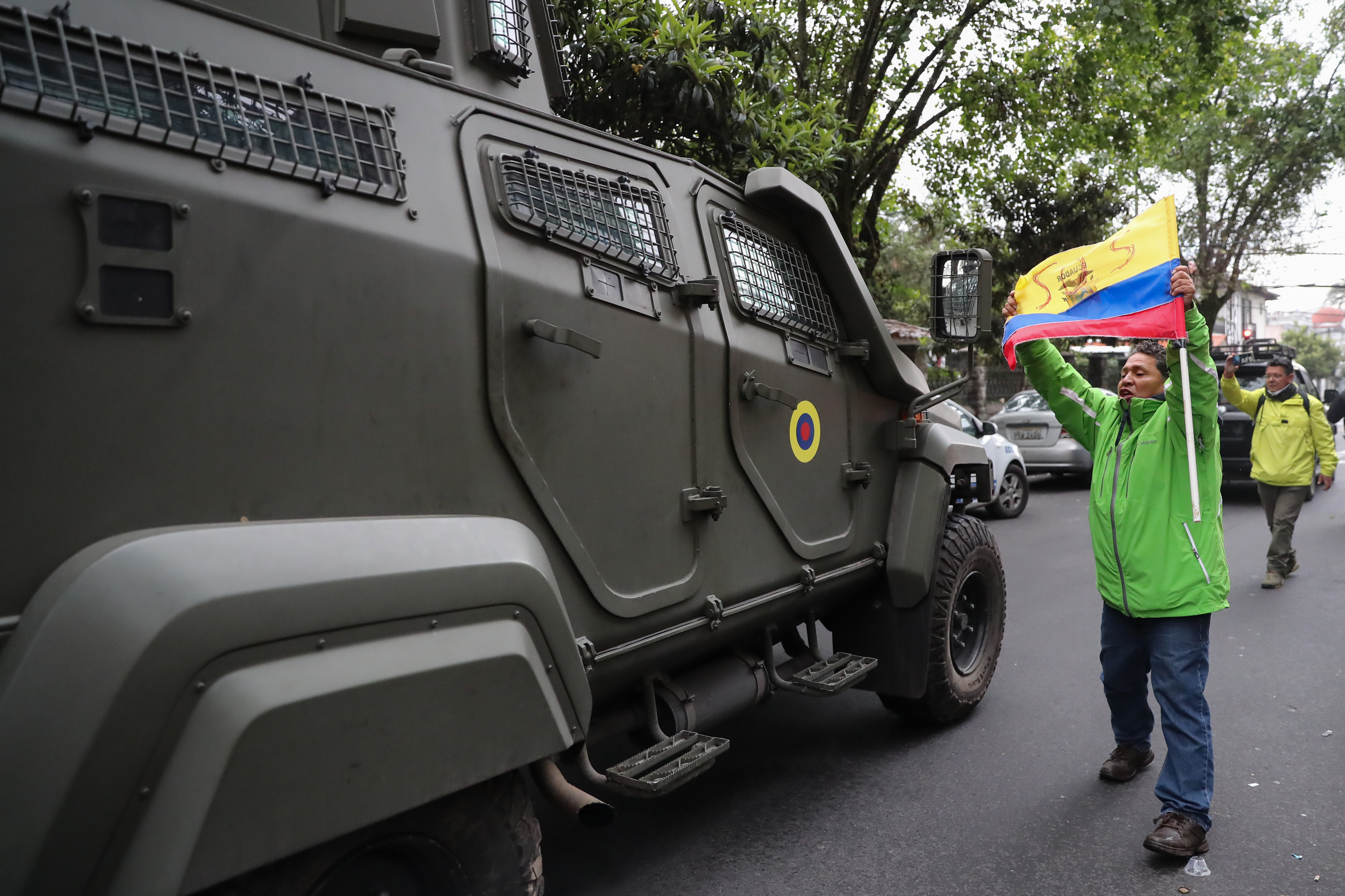 -FOTODELDÍA- QUI01. QUITO (ECUADOR), 06/04/2024.-  Un hombre exhibe una bandera mientras pasa un vehículo blindado donde es trasladado el exvicepresidente ecuatoriano Jorge Glas, este sábado en Quito (Ecuador). El Gobierno de Ecuador entró en la noche del viernes a la Embajada de México en Quito y detuvo a Jorge Glas, exvicepresidente de Rafael Correa (2007-2017), después de que el Gobierno mexicano le hubiese concedido el asilo político que había solicitado. EFE/ José Jácome