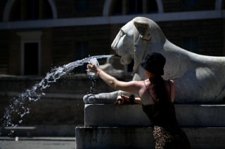 (FILES) A woman fills her bottle with water at the Lions fountain at Piazza del Popolo on July 12, 2024 in Rome where temperatures are expected to rise to 36 degrees celsius.