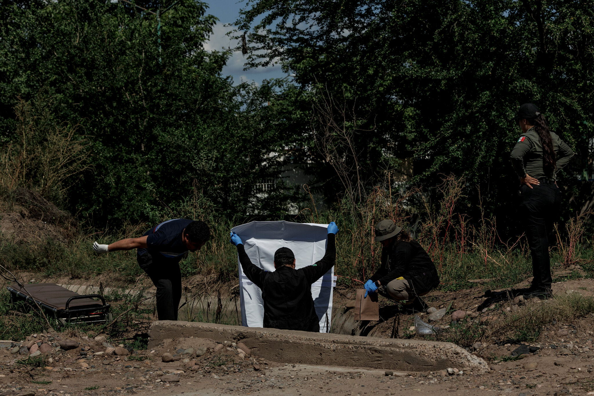 Un trabajador funerario, a la izquierda, ayuda a las autoridades locales a recuperar un cadáver en un campo a las afueras de Culiacán.