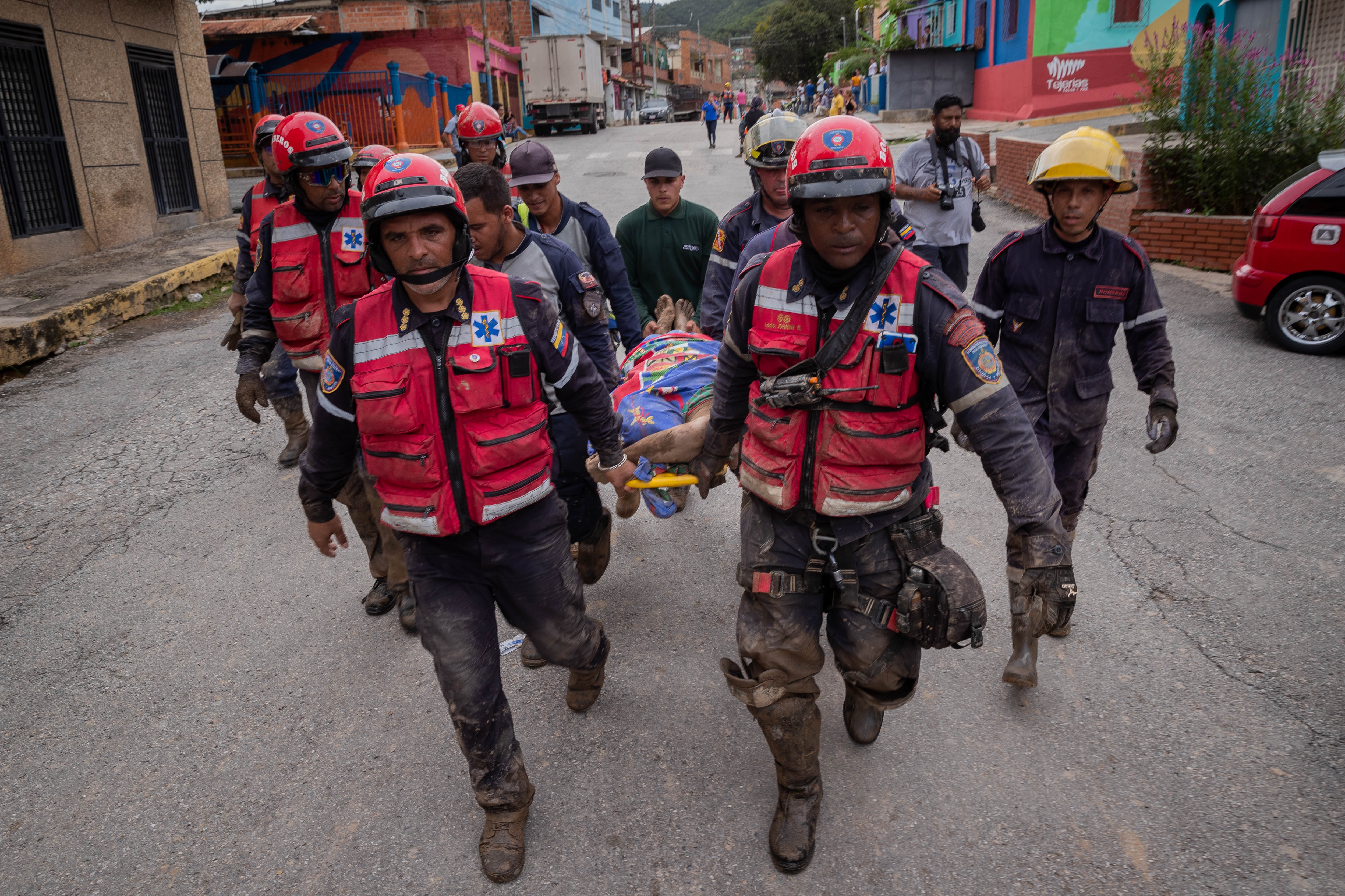 AME3286. TEJERIAS (VENEZUELA), 09/10/2022.- Bomberos trasladan a un hombre fallecido durante las lluvias y desbordamiento de la quebrada (rio) Los Patos, hoy en Las Tejerias(Venezuela). La crecida de una quebrada este sábado arrastró viviendas, mobiliario urbano, e inundó las calles de la localidad, arrasando con todo lo que el agua encontró a su paso. El Gobierno desplegó hoy organismos de salvamento, seguridad ciudadana, así como cuadrillas de mantenimiento y limpieza, y personal de diversas instituciones para "la atención integral del pueblo", dijo el presidente Nicolás Maduro a través de su cuenta de Twitter.EFE/ Rayner Peña R.